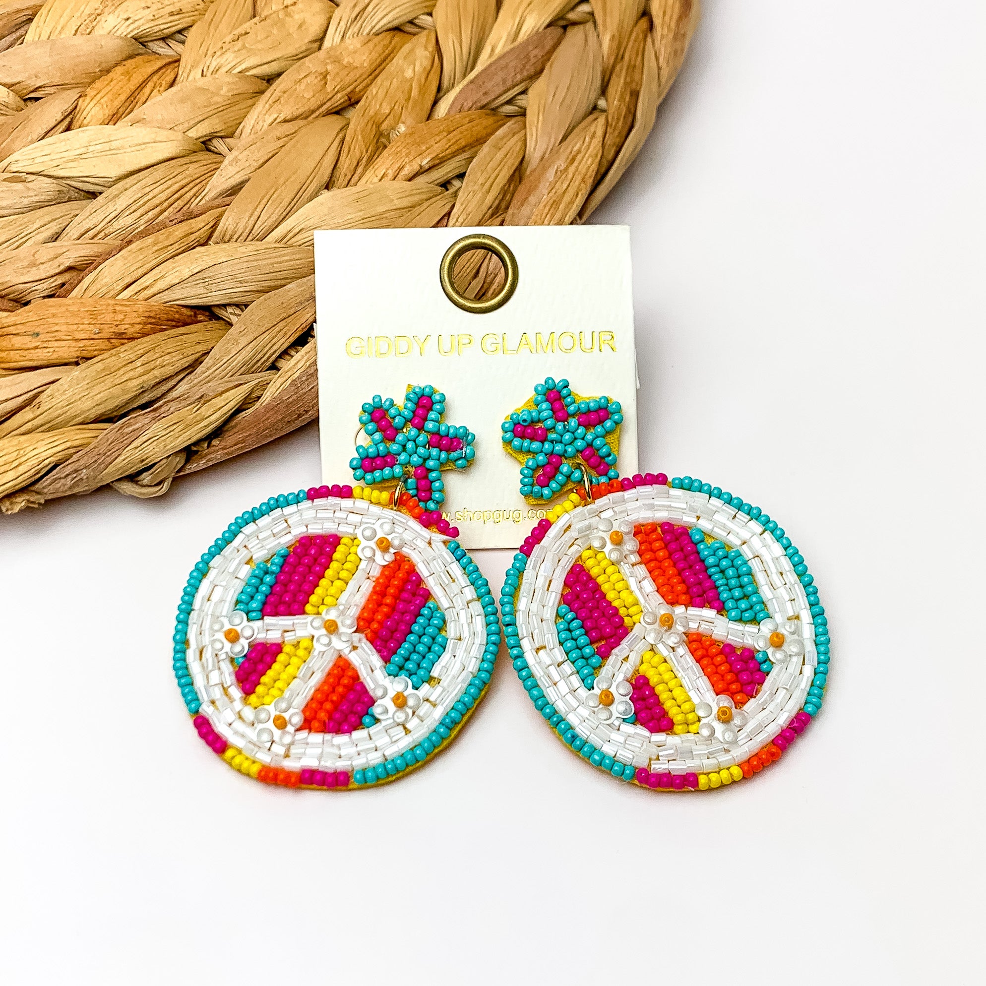 Beaded Peace sign Earrings With Star Post in Multicolor. Pictured on a white background with a wood like decoration in the top left corner.