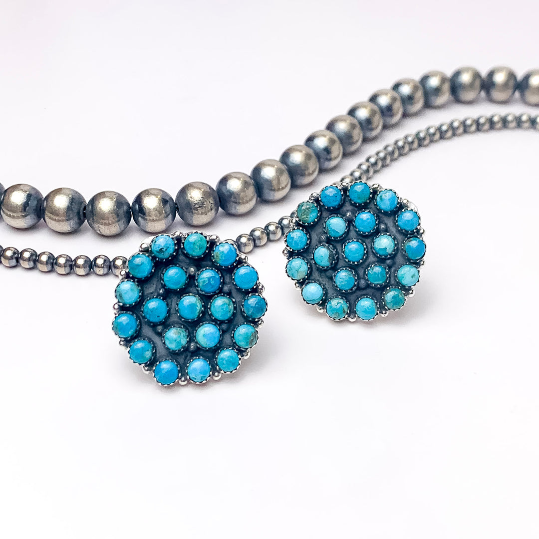 In the picture are sterling silver circle cluster kingman turquoise stone rings with a white background