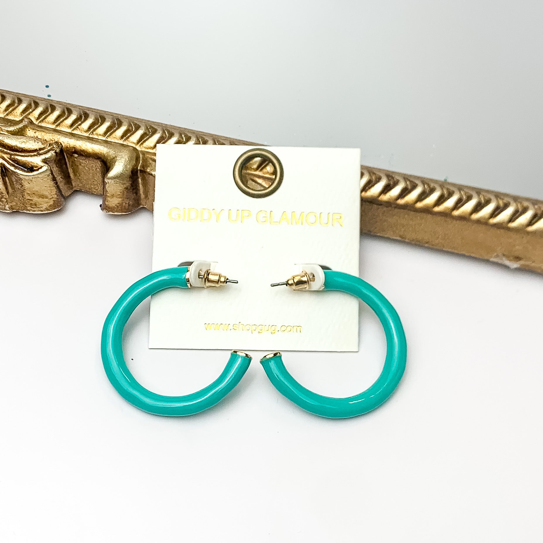 Plan For Cabo Small Hoop Earrings in Turquoise Green. Pictured on a white background with a gold frame behind the earrings.