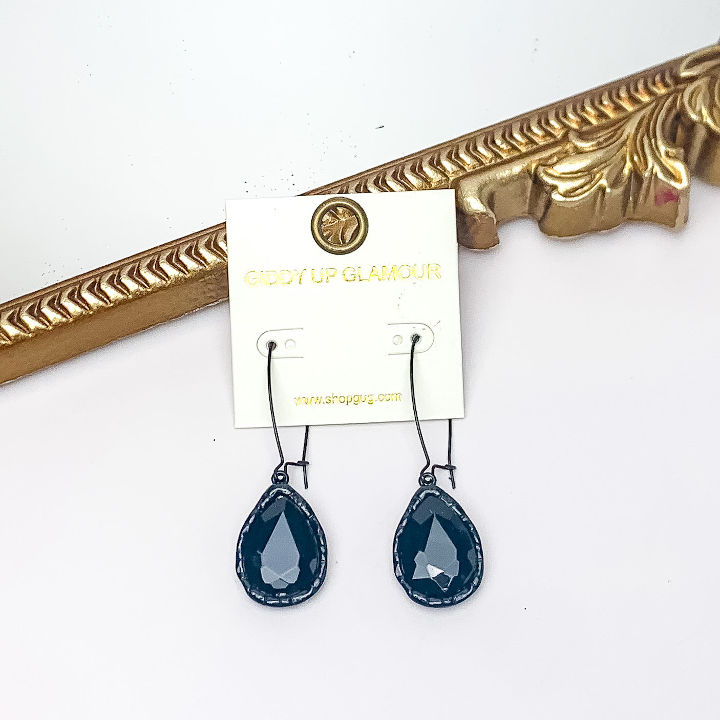 Radiant Kidney Wire Teardrop Earrings With Crystals in Black. Pictured on a white background with a gold frame in the background.