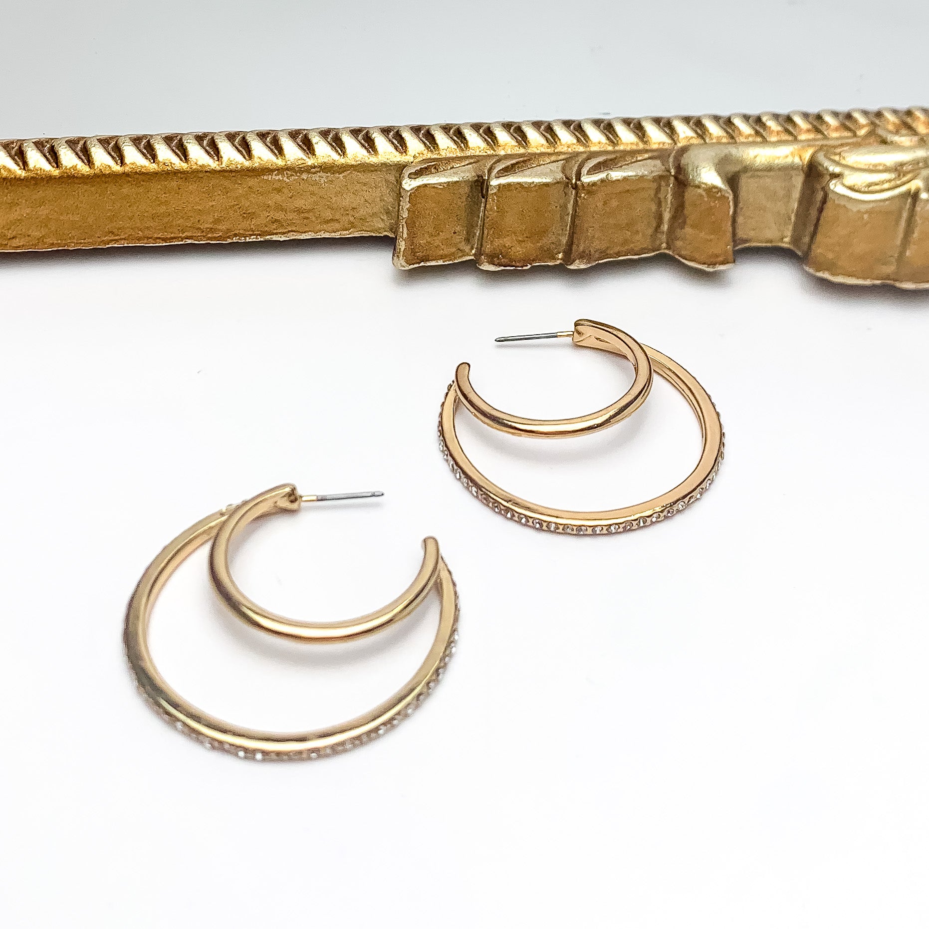 Midnight Hour Gold Tone Hoop Earrings With Clear Crystals. Pictured on a white background with a gold frame above the earrings.