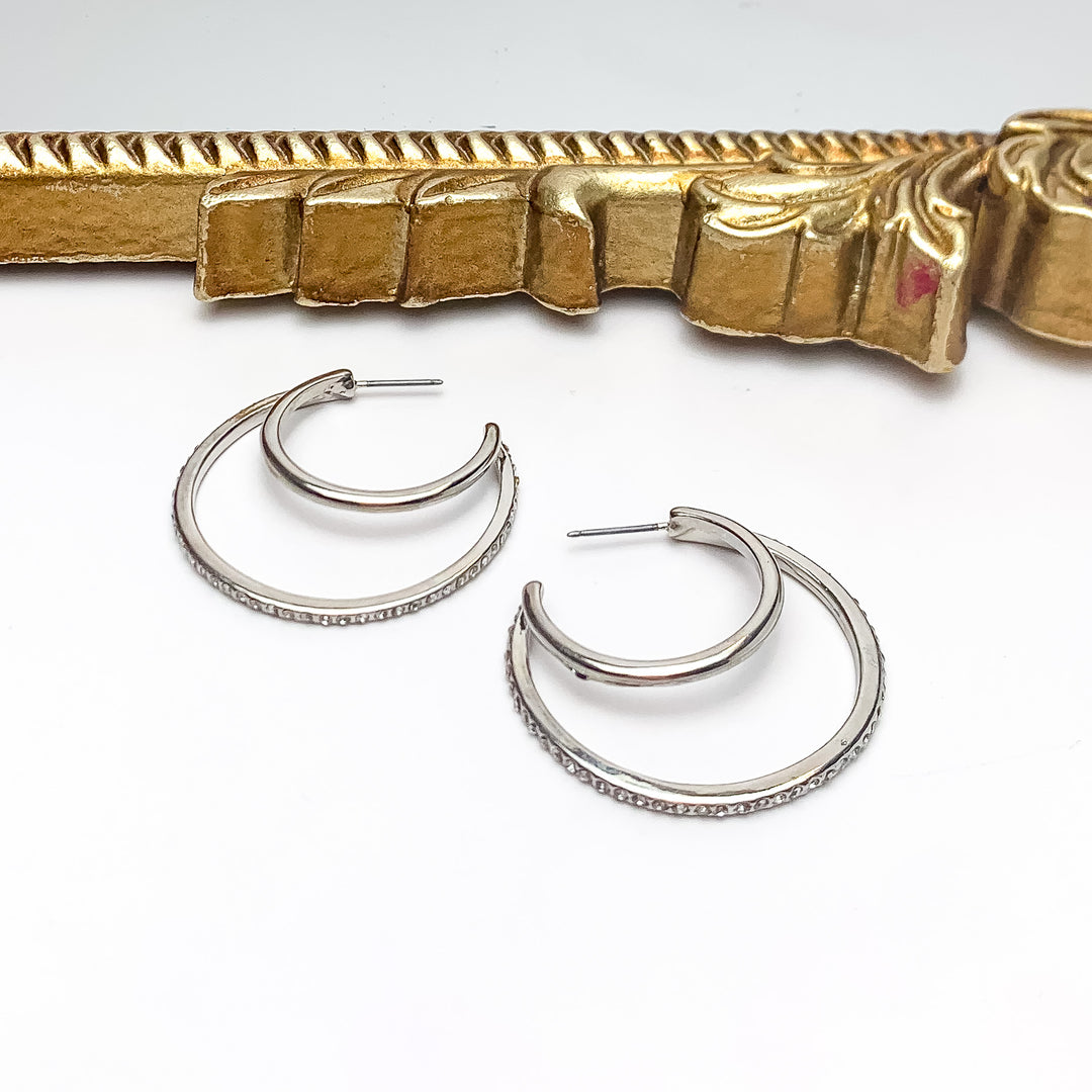 Midnight Hour Silver Tone Hoop Earrings With Clear Crystals. Pictured on a white background with a gold frame above the earrings.