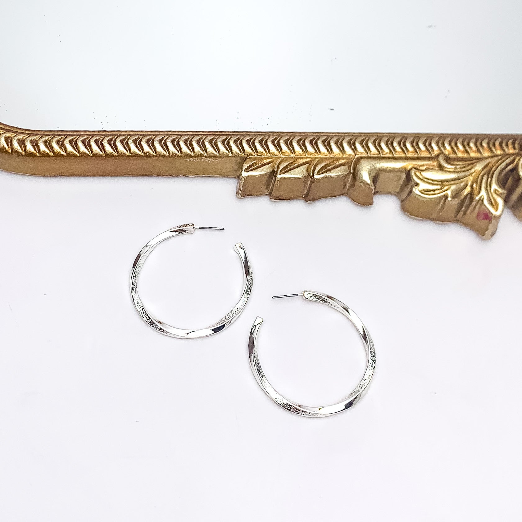 City Day Large Silver Tone Hoop Earrings. Pictured on a white background with a gold frame above the earrings.