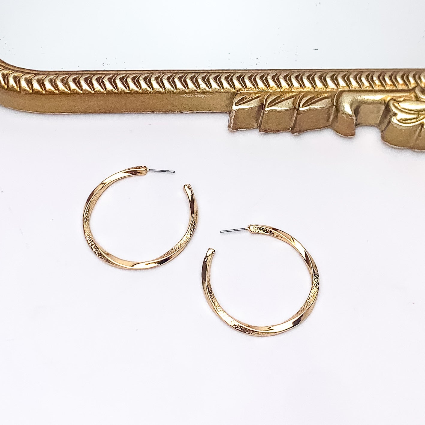 City Day Large Gold Tone Hoop Earrings. Pictured on a white background with a gold frame above the earrings.
