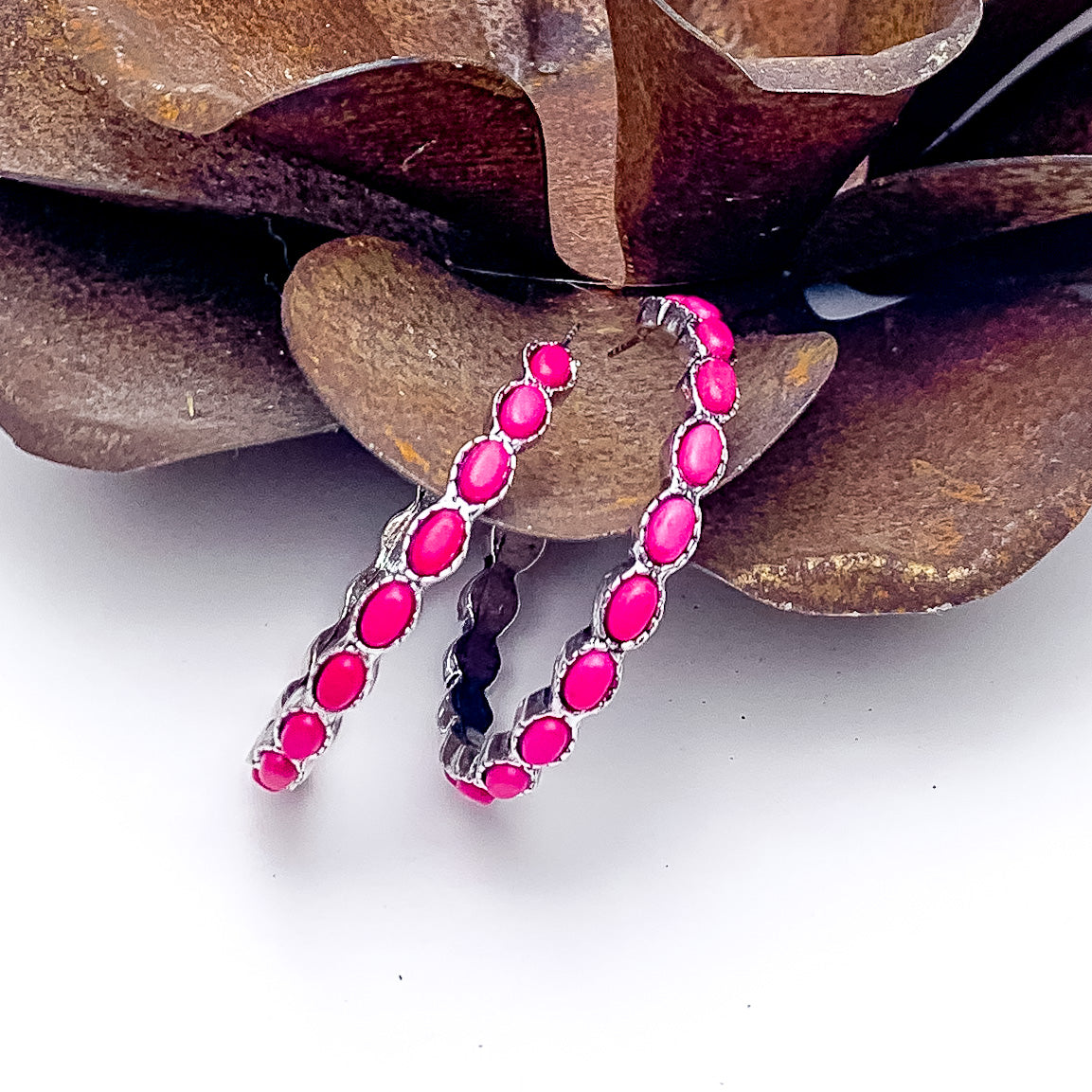 Silver Hoop Earrings with Fuchsia Stones. Pictured on a white background with the earrings against a rustic rose.