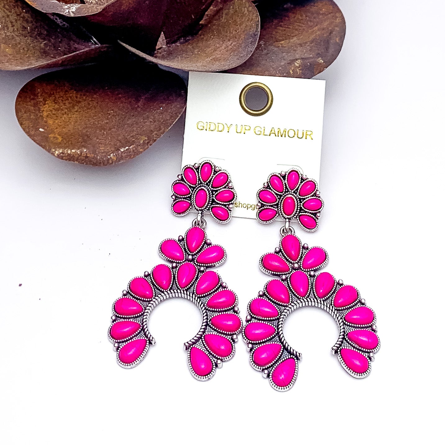 Western Naja Earrings in Silver Tone with Fuchsia Stones. Pictured on awhite background with a metal piece in the top left corner.