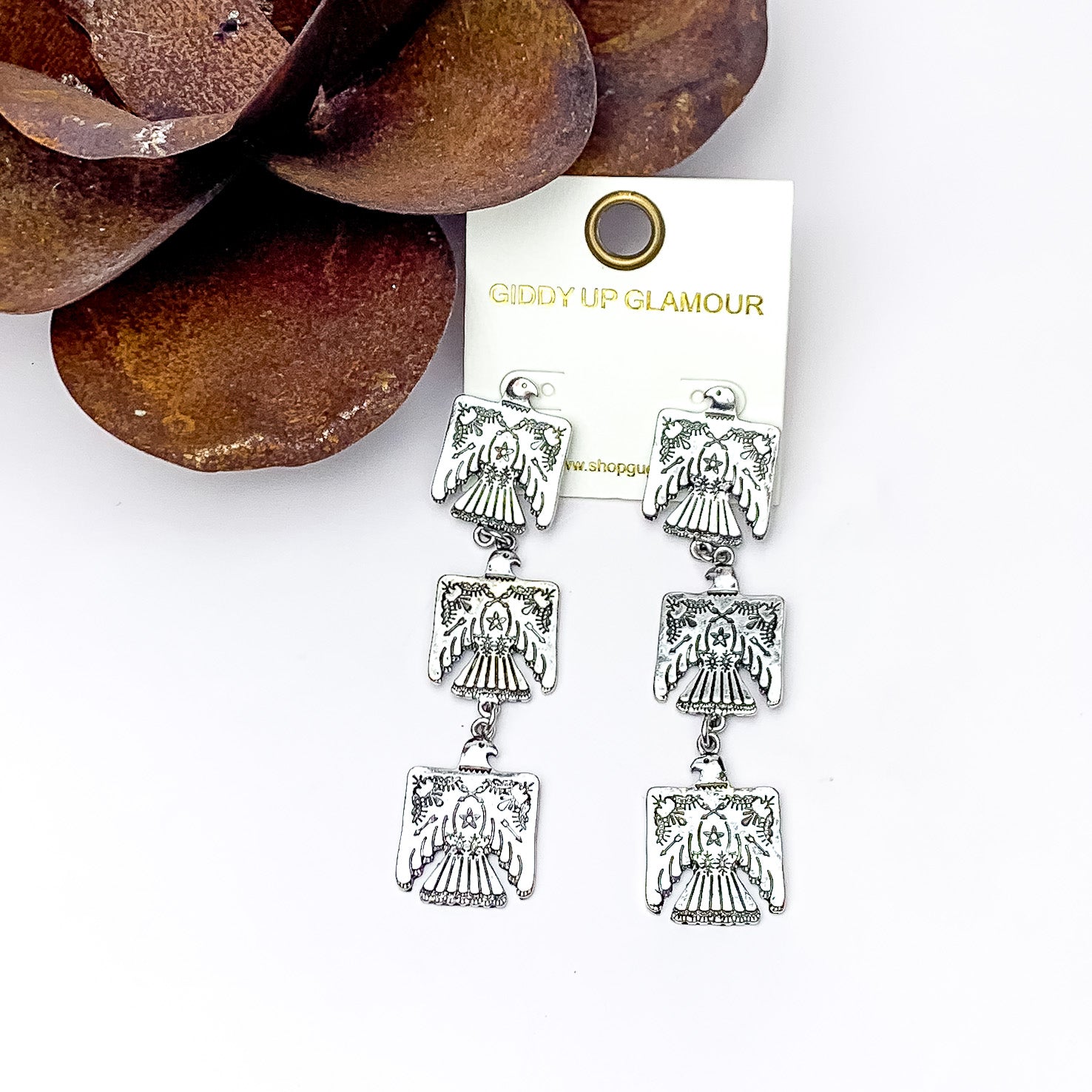 Silver Tone Free bird Three Tier Earrings. Pictured on a white background with a metal flower in the top left corner.