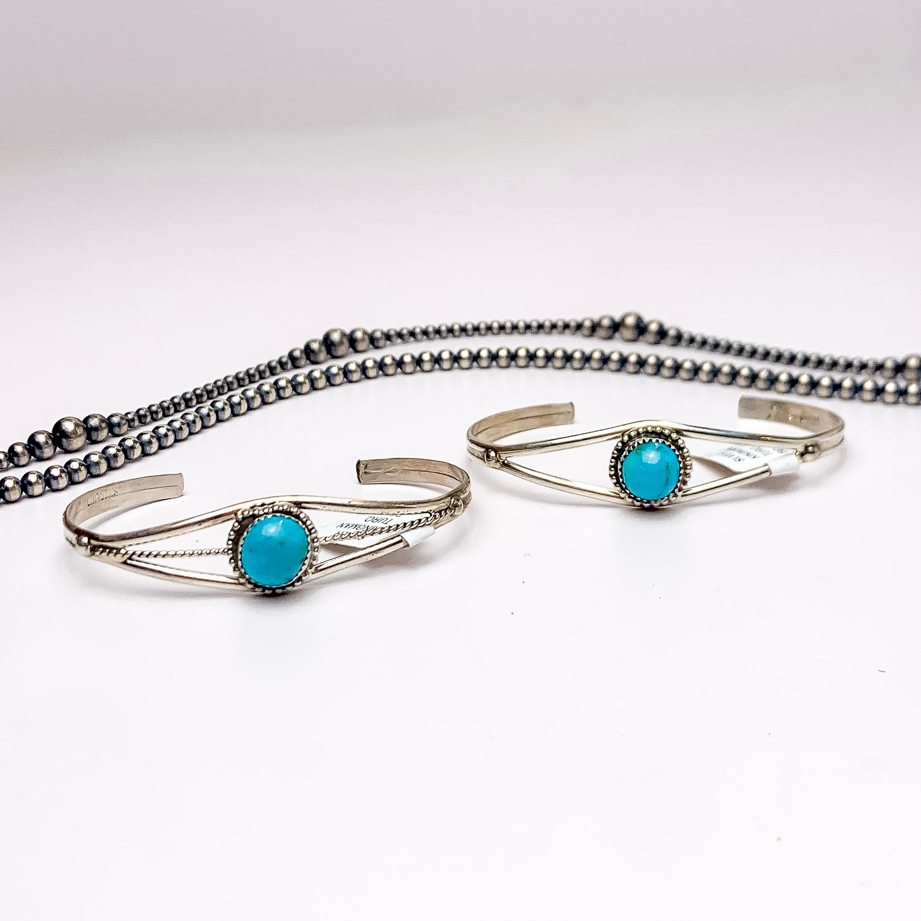 In the picture is a sterling silver cuff bracelet with a turquoise center stone with a white background