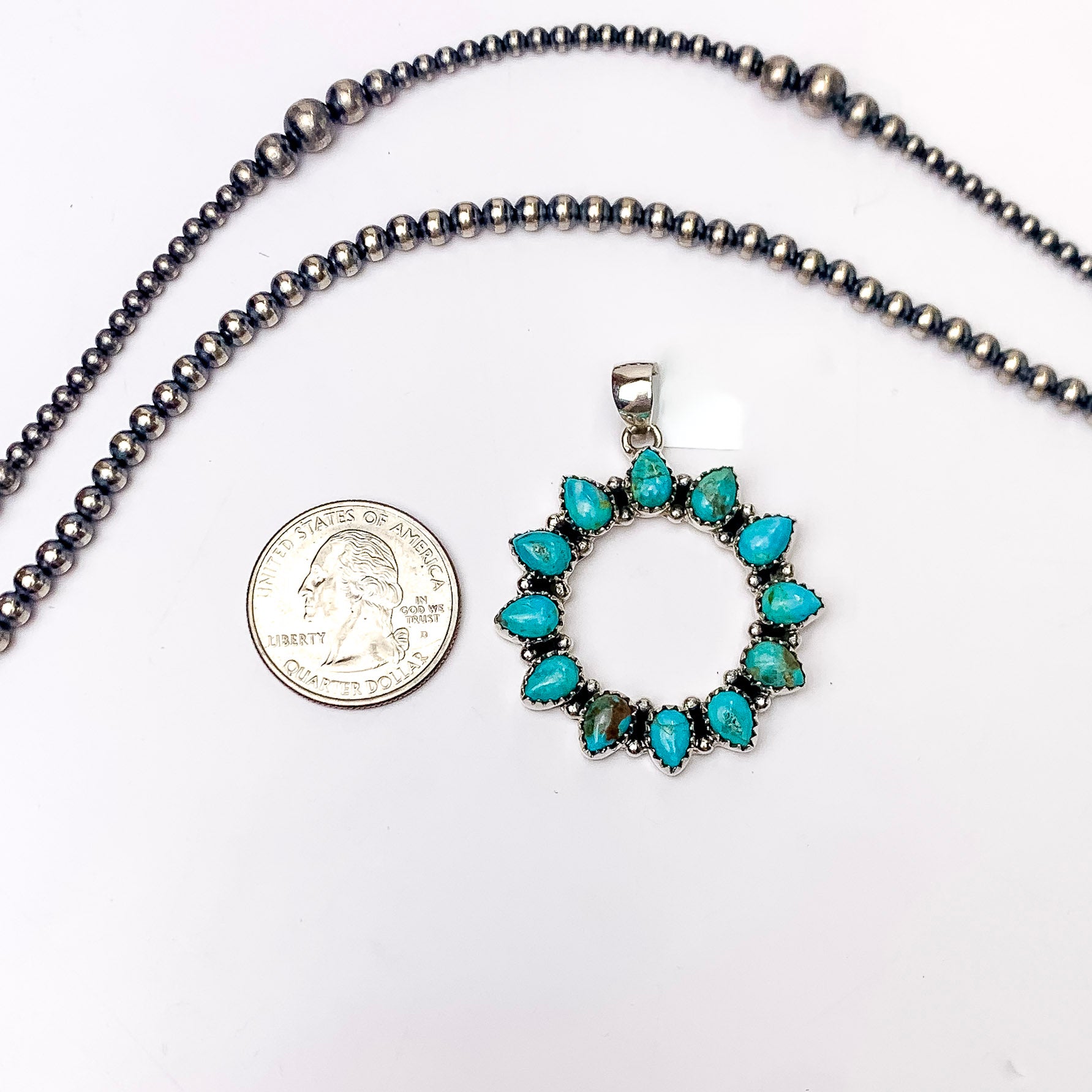 In the picture is a  handmade round pendant includes genuine sterling silver and genuine kingman turquoise stones with a white background