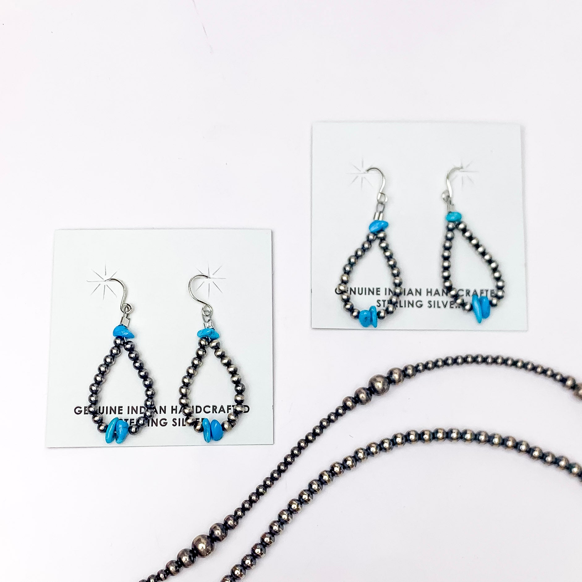 In the picture are hand-strung Navajo earrings with a teardrop design with a pop of turquoise beaded in the center with a white background 