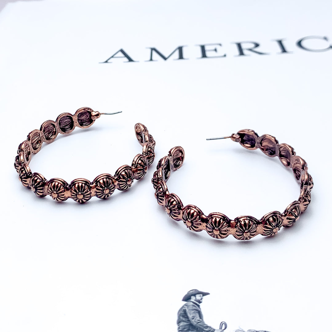 Copper Tone Large Western Earrings With Circle Designs. Pictured on a white background with words and a cowboy at the bottom.