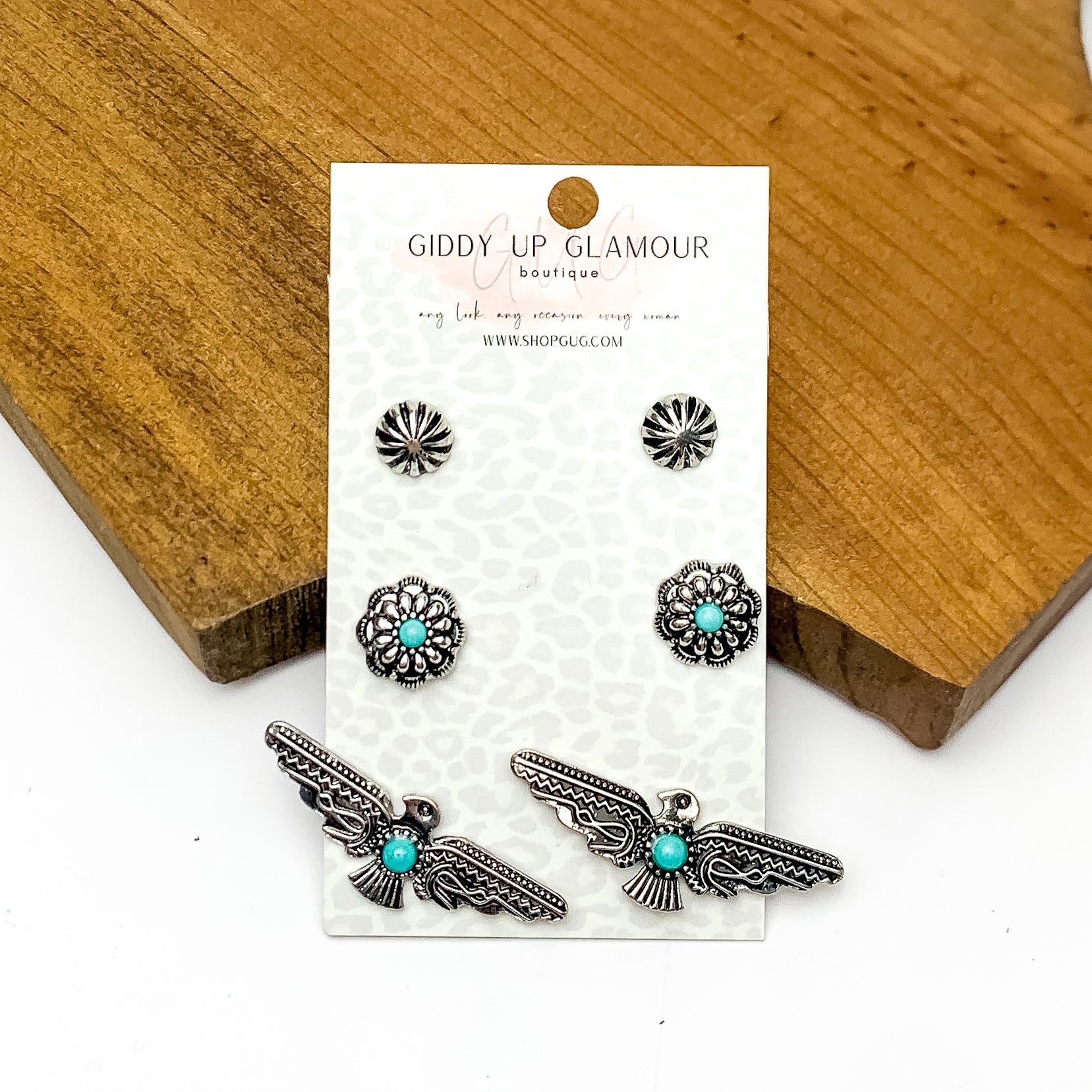 Set Of Three | Silver Tone designed earrings With Turquoise Stones. Pictured on a white background with the earrings against a wood piece.