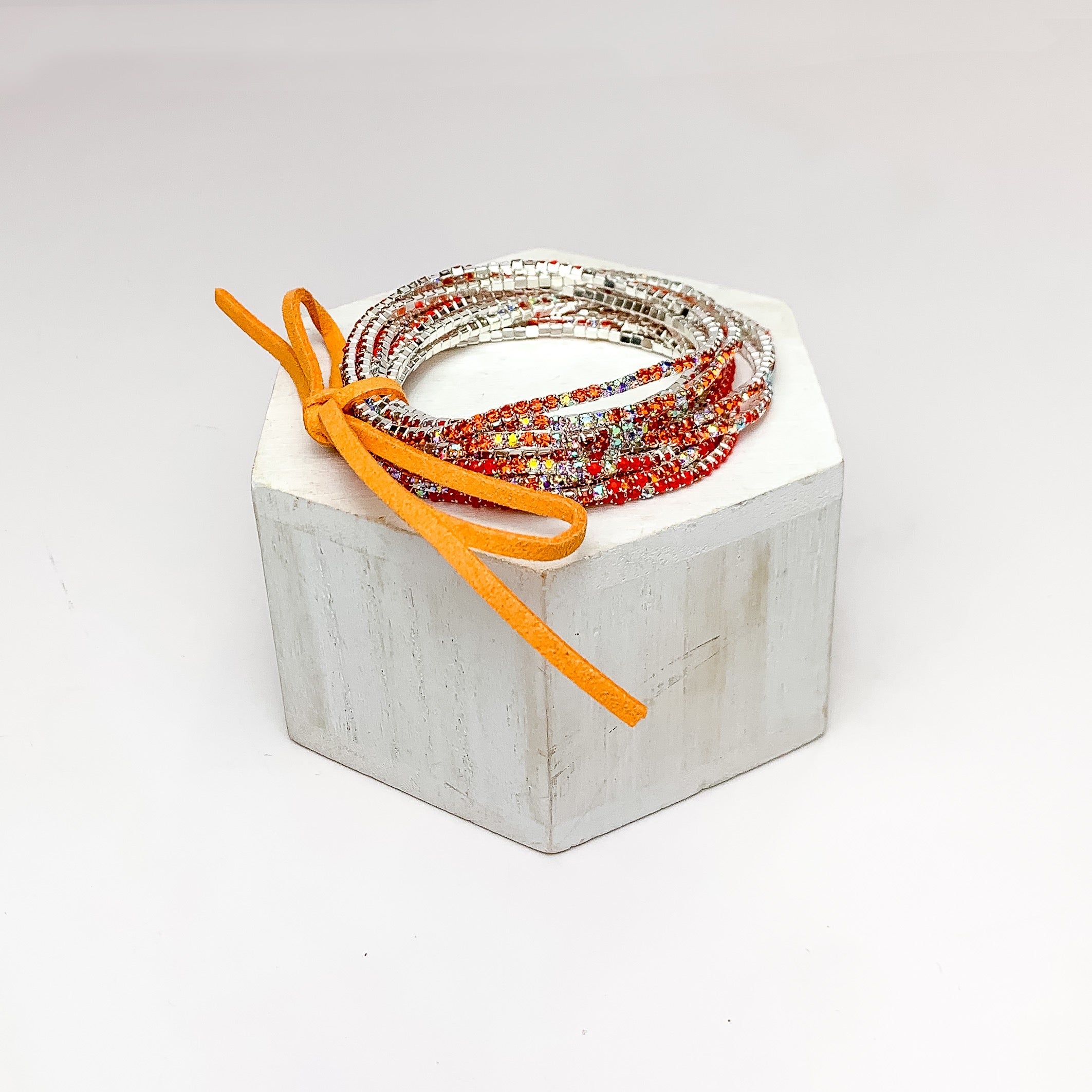 Day Party Crystals Stretchy Bracelet Set With Bow in Orange. Pictured on a white background with the jewelry sitting on a white podium.