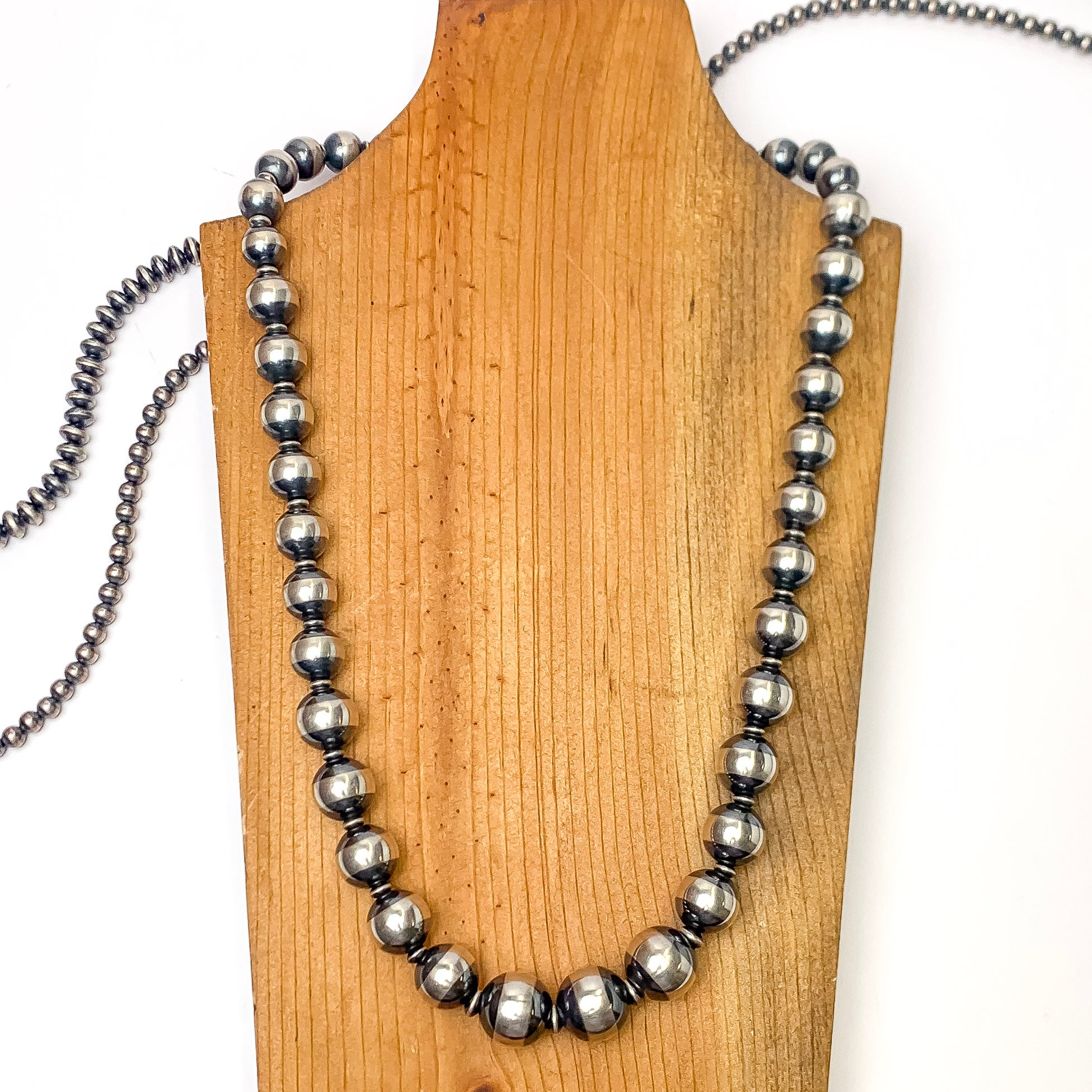In the picture is a handmade sterling silver saucer Navajo pearl necklace with a white background