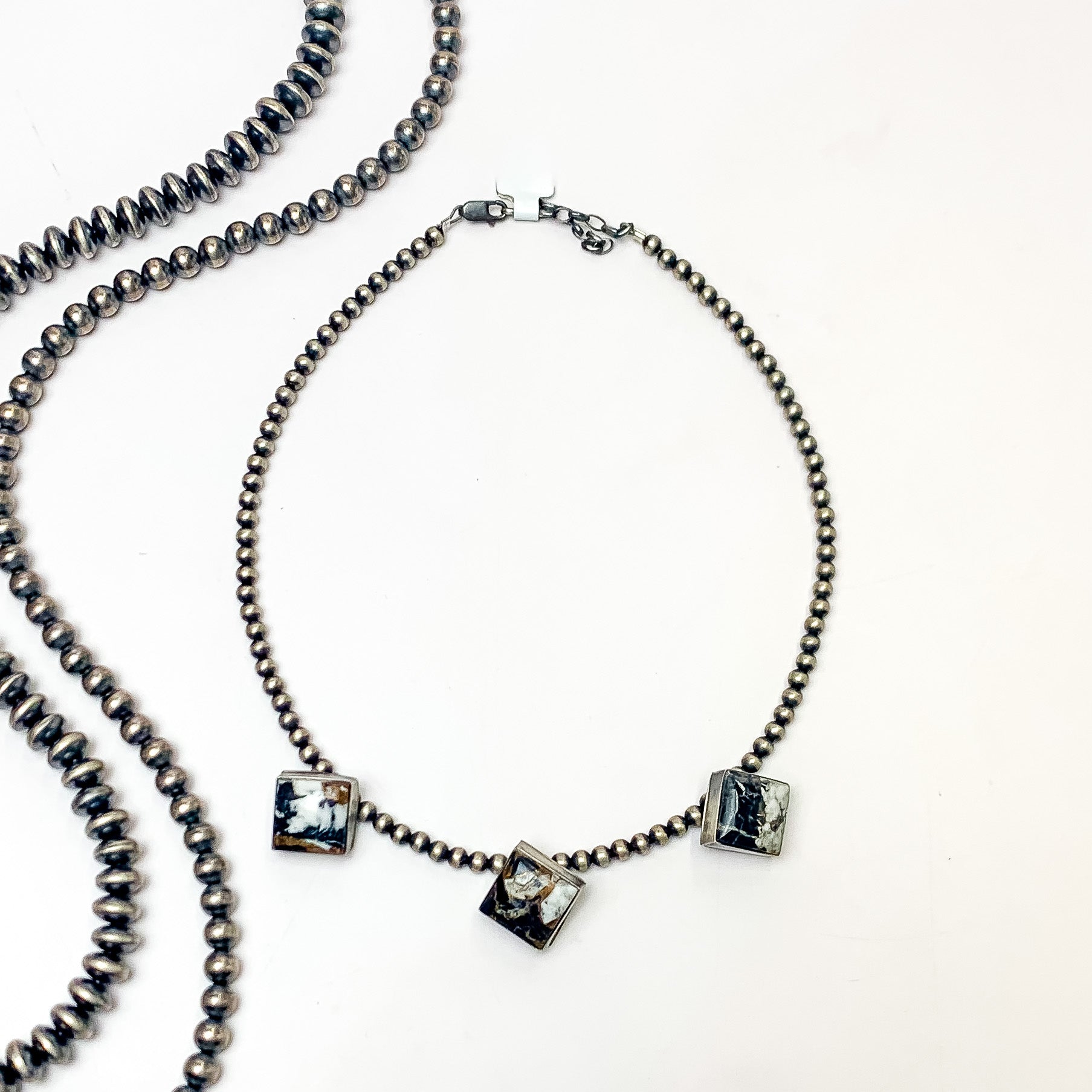 Pictured is a silver pearl beaded necklace with three diamond stones. These stones are white buffalo stones. This necklace is pictured on a white background with silver beads on the left side. 