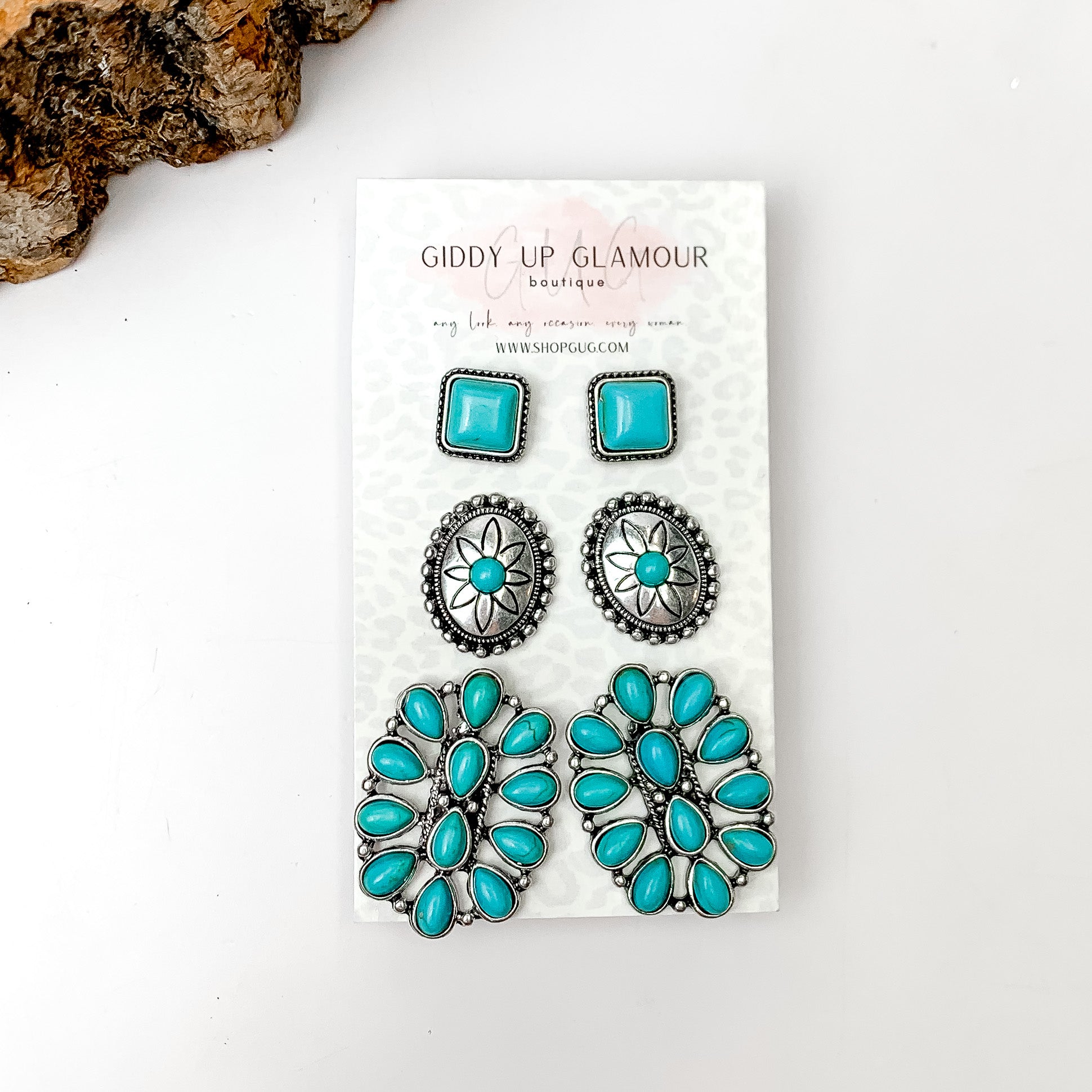 Set Of Three | Western Turquoise Stones and Silver Tone Stud Earrings. Pictured on a white background with a piece of wood in the top left corner.