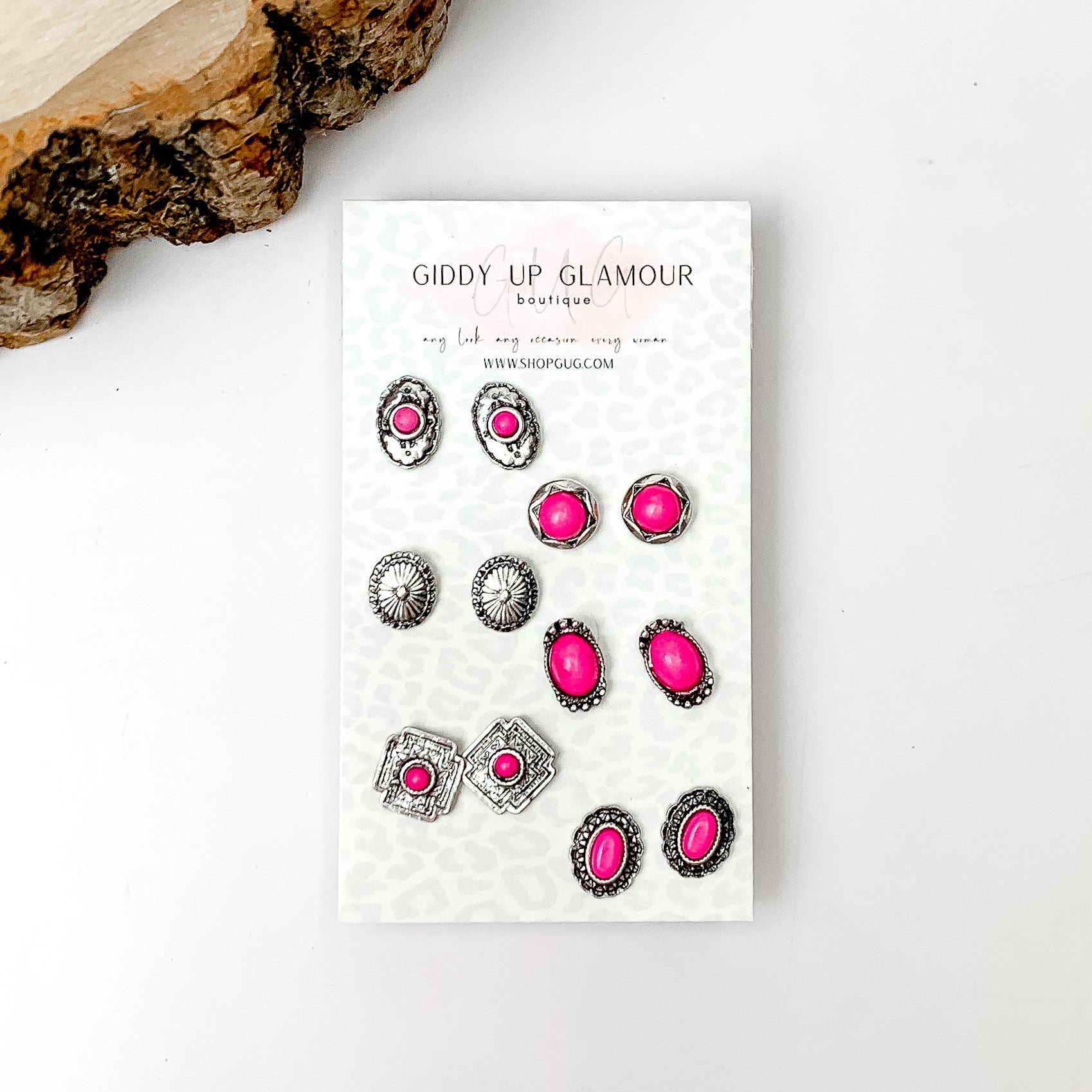 Set Of Six | Western Small Fuchsia Pink Stones and Silver Tone Stud Earrings. Pictured on a white background with a wood piece in the top left corner.