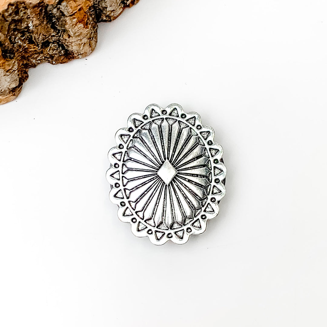 Silver Tone Oval Phone Grip. Pictured on a white background with a wood piece in the top left corner.