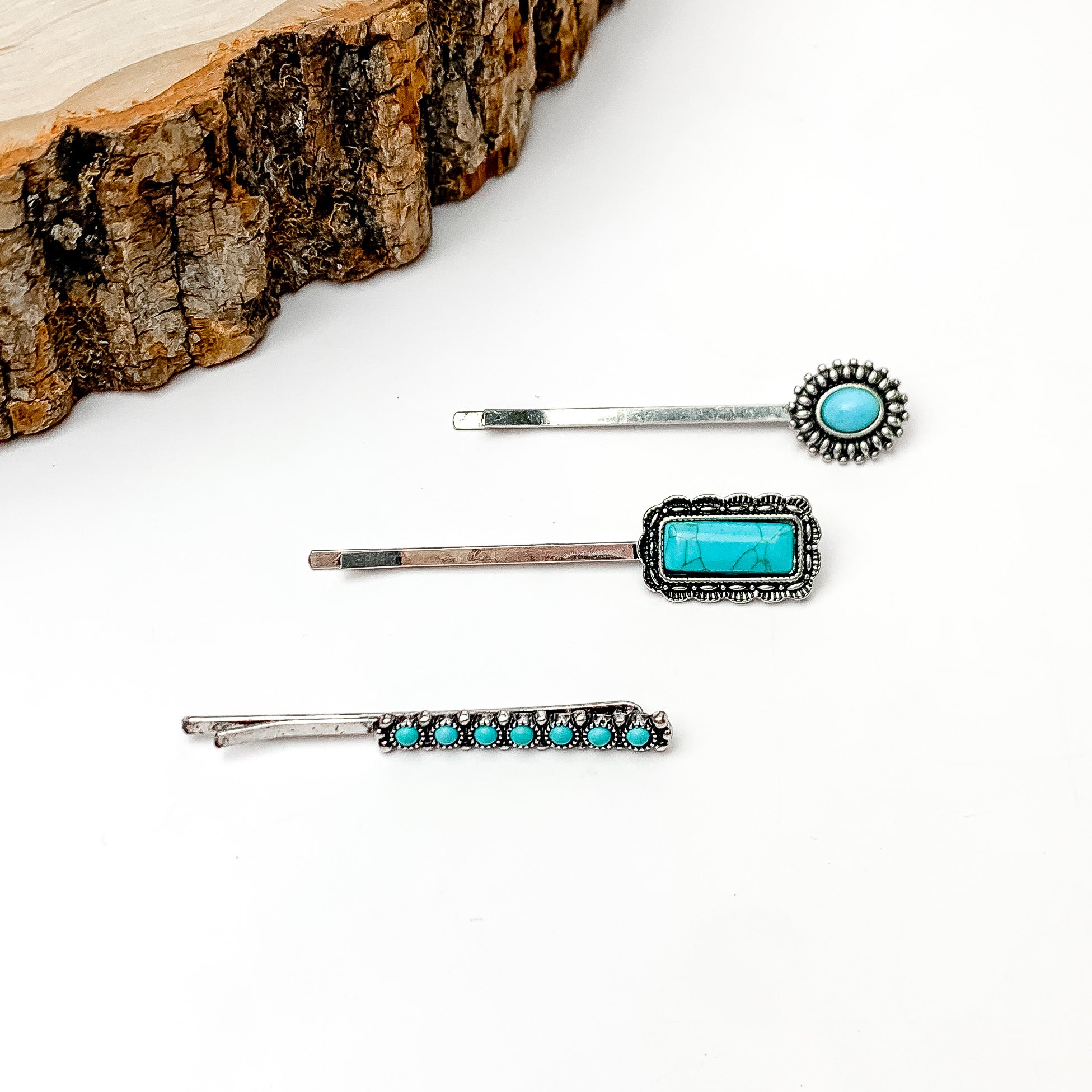 Set of Three | Western Designed Faux Turquoise Stone Hair Pins in Silver Tone. Pictured on a white background with a wood piece in the top left corner.