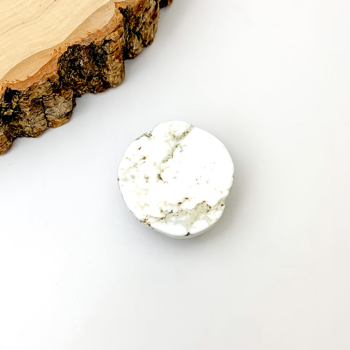 White Marble Slab Circular Phone Grip. Pictured on a white background with a wood piece in the top left corner.