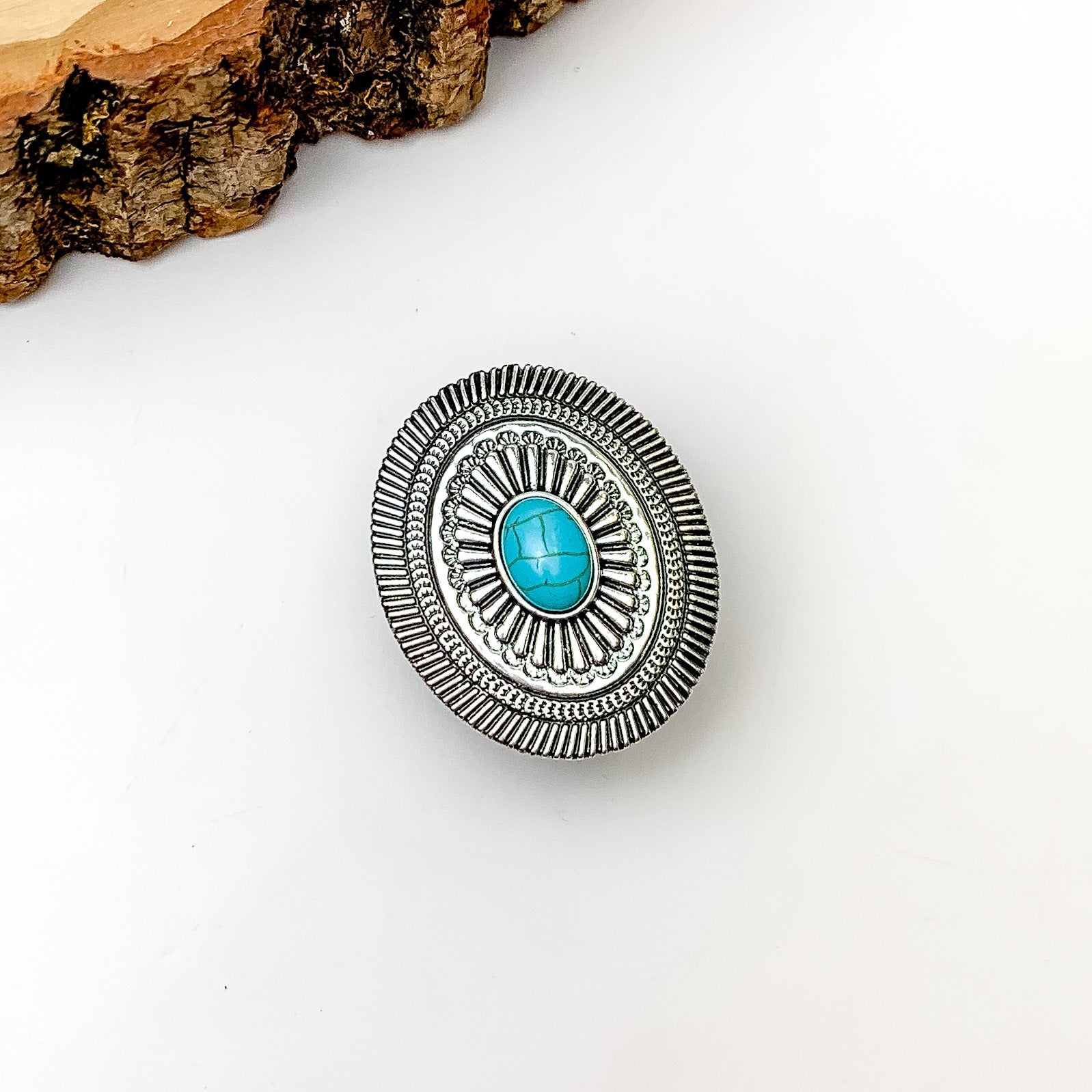 Silver Tone Oval With Turquoise Stone Phone Grip. Pictured on a white background with a wood piece in the top left corner.