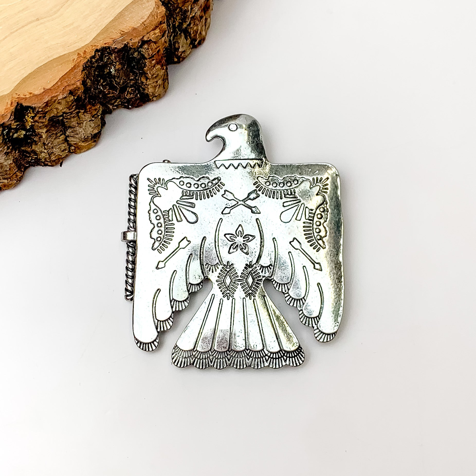 Free Bird Belt Buckle in Silver Tone. Pictured on a white background with a wood piece in the top left corner.