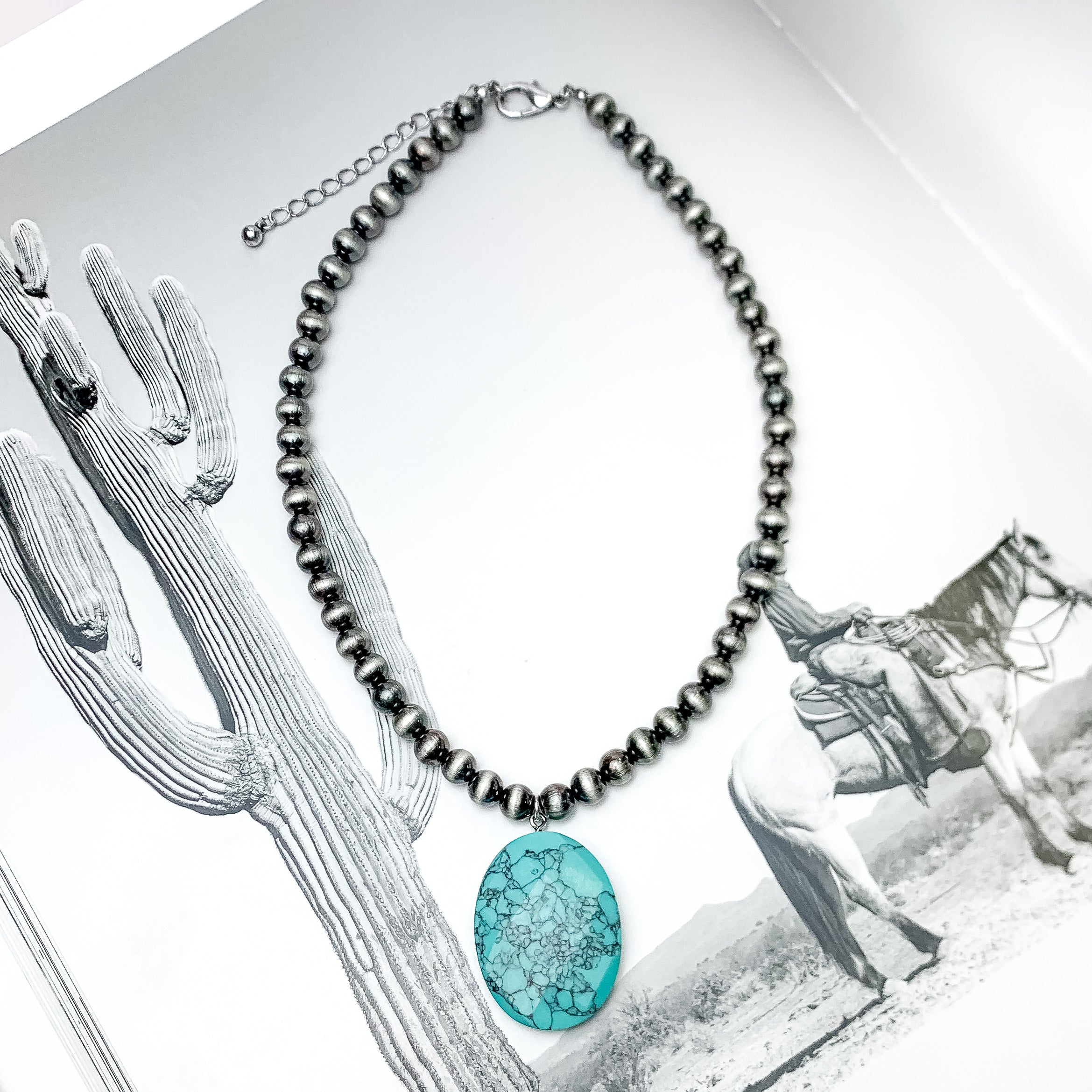 Silver Tone Beaded Necklace With Turquoise Stone. Pictured on a western themed background.