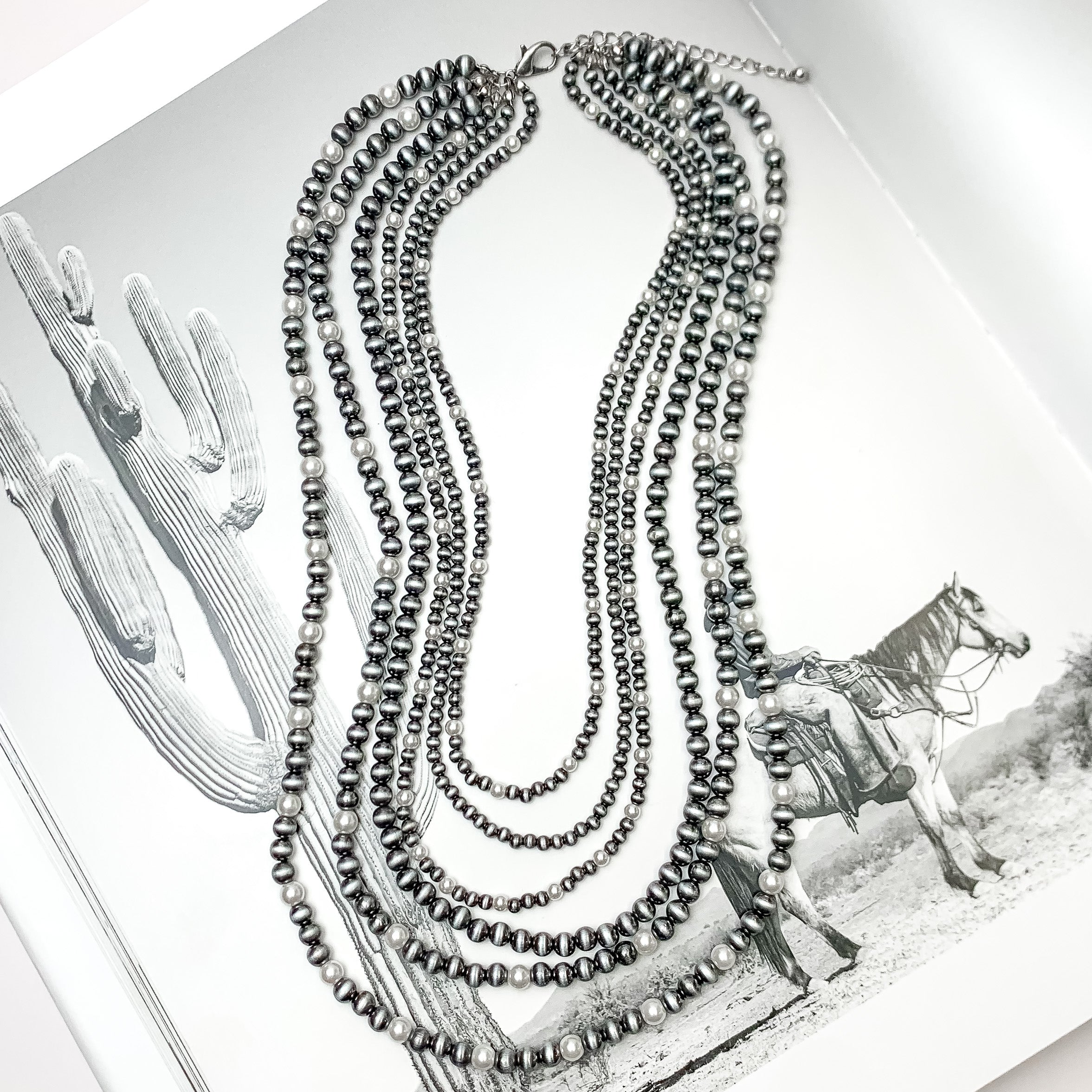 Six Strand Faux Navajo Pearl Necklace in Silver Tone with White Pearl Beads. Pictured on a western background.