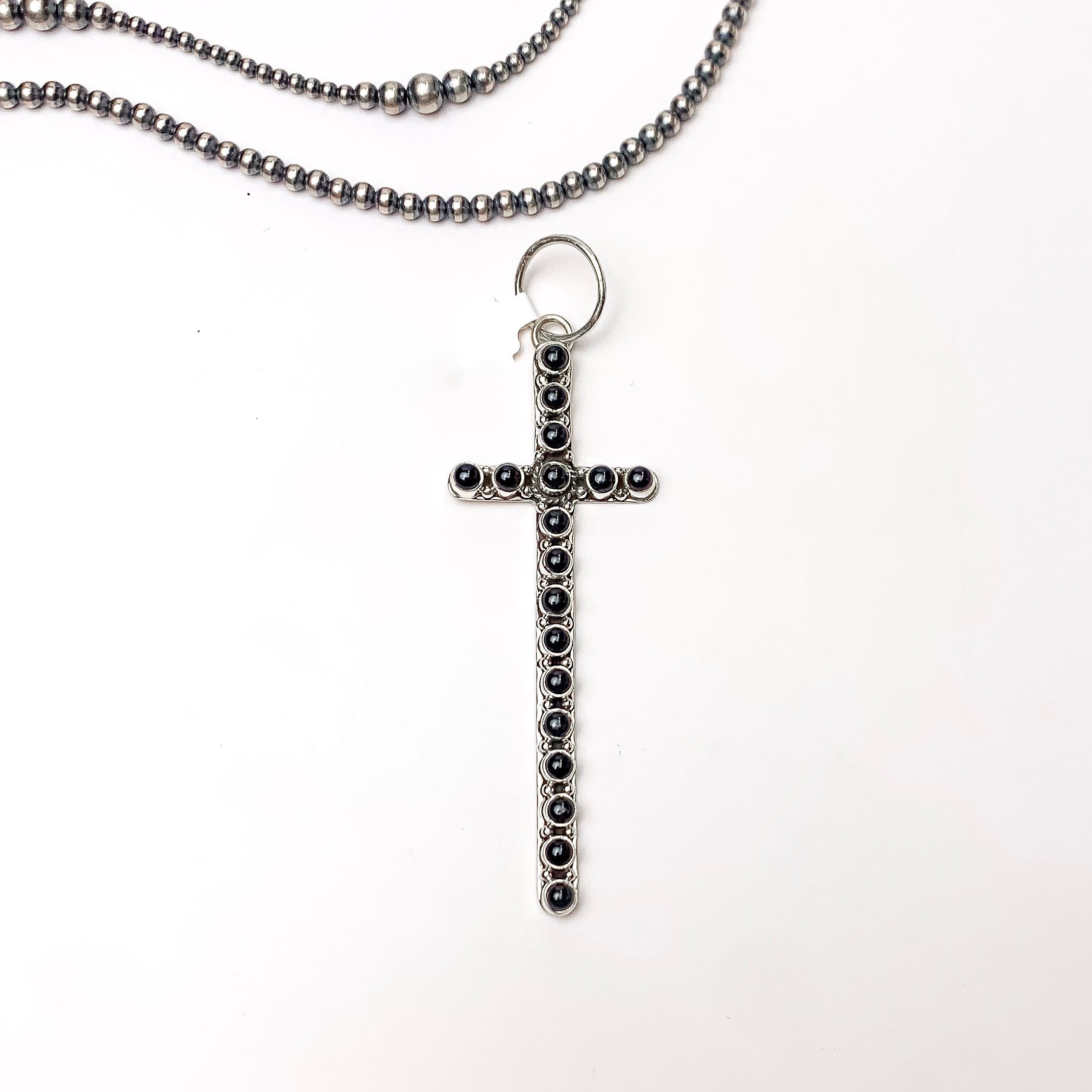 In the picture is a black onyix cross pendant with a white background