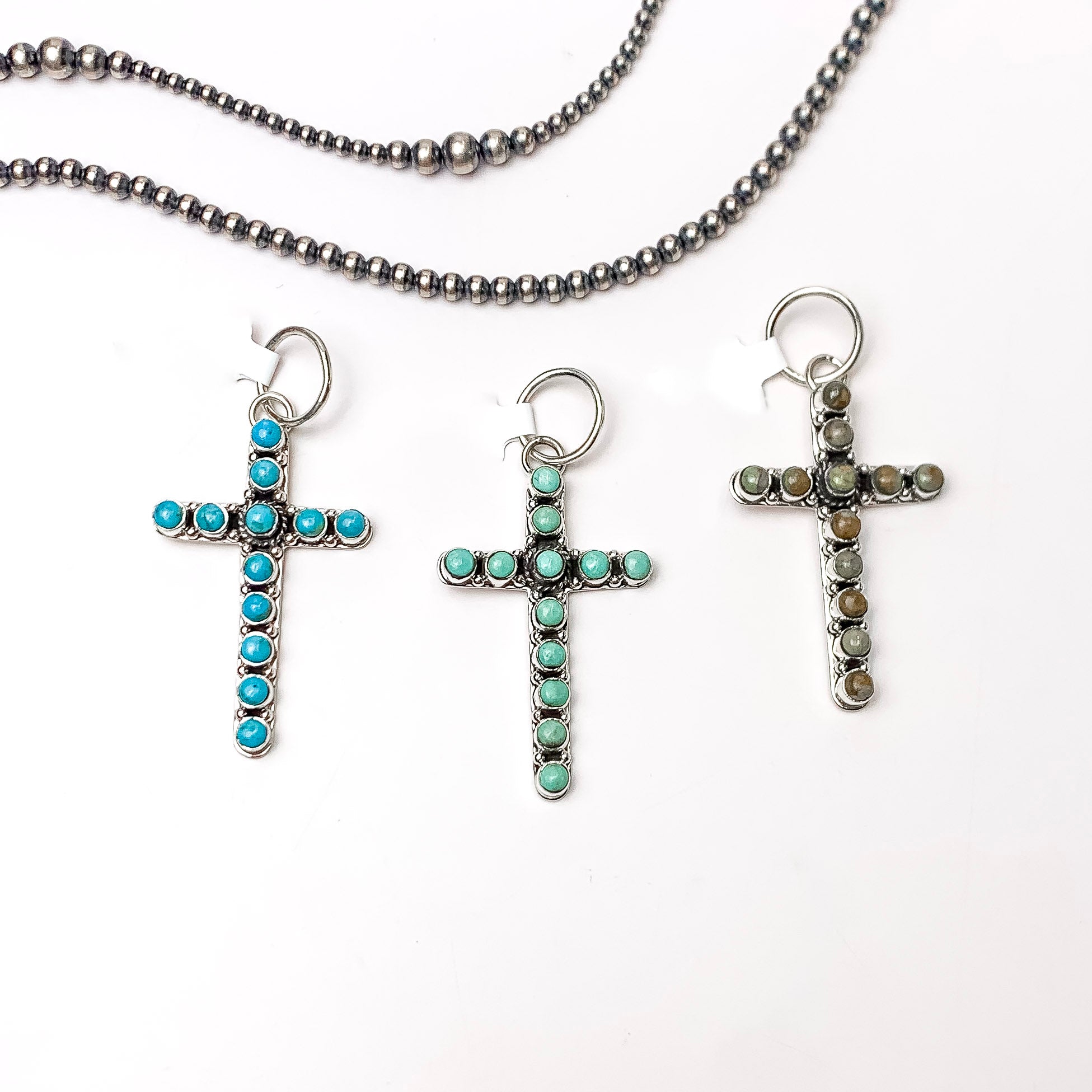 In the picture sterling silver and kingman turquoise small cross pendant with a white background