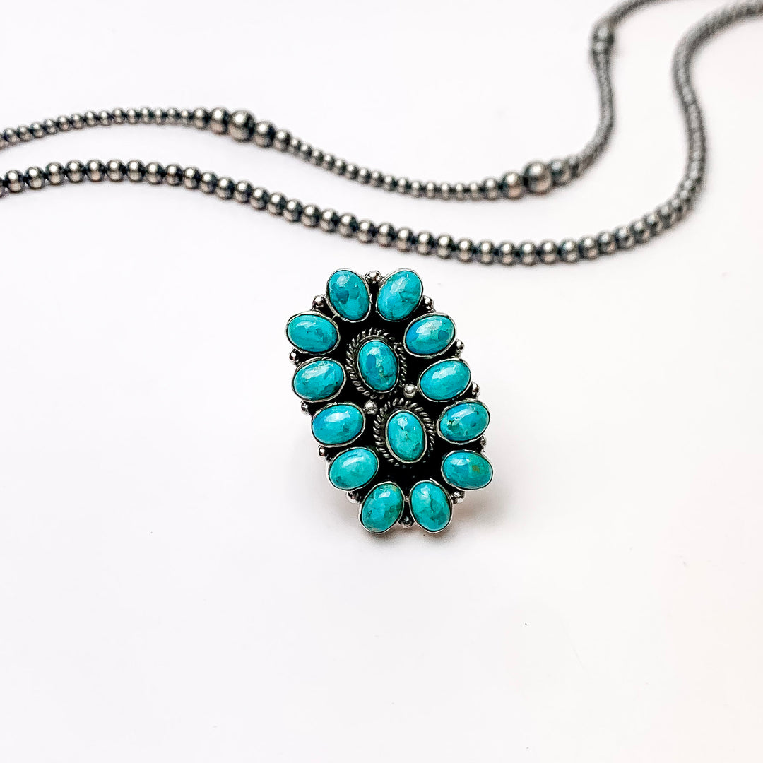 In the picture are sterling silver adjustable long oval kingman turquoise cluster ring with a white background