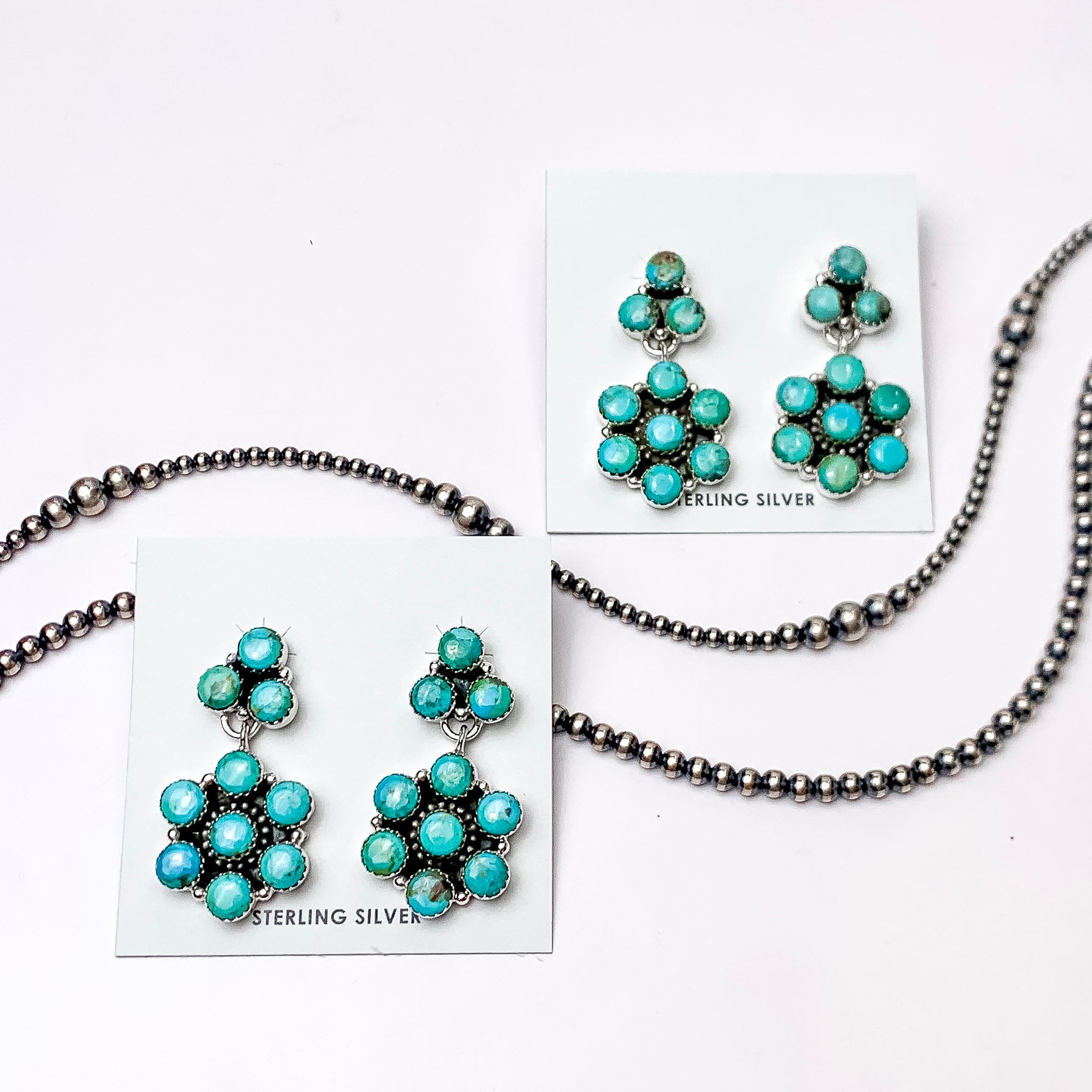 In the picture are sterling silver circle cluster stud with a flower drop earrings in kingman turquoise with a white background