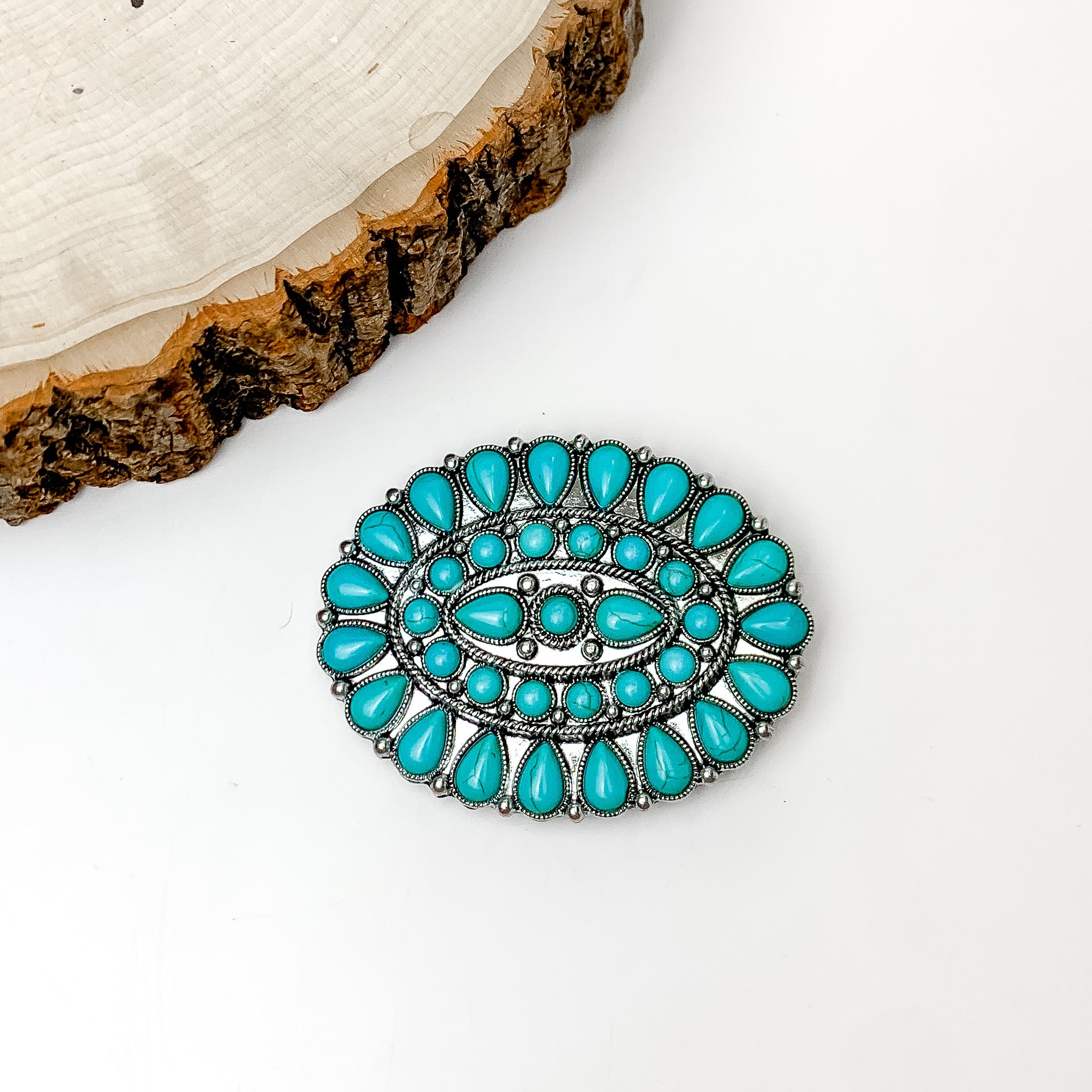 Turquoise Blue Stoned Oval Belt Buckle in Silver Tone. Pictured on a white background with a wood piece in the top left corner.