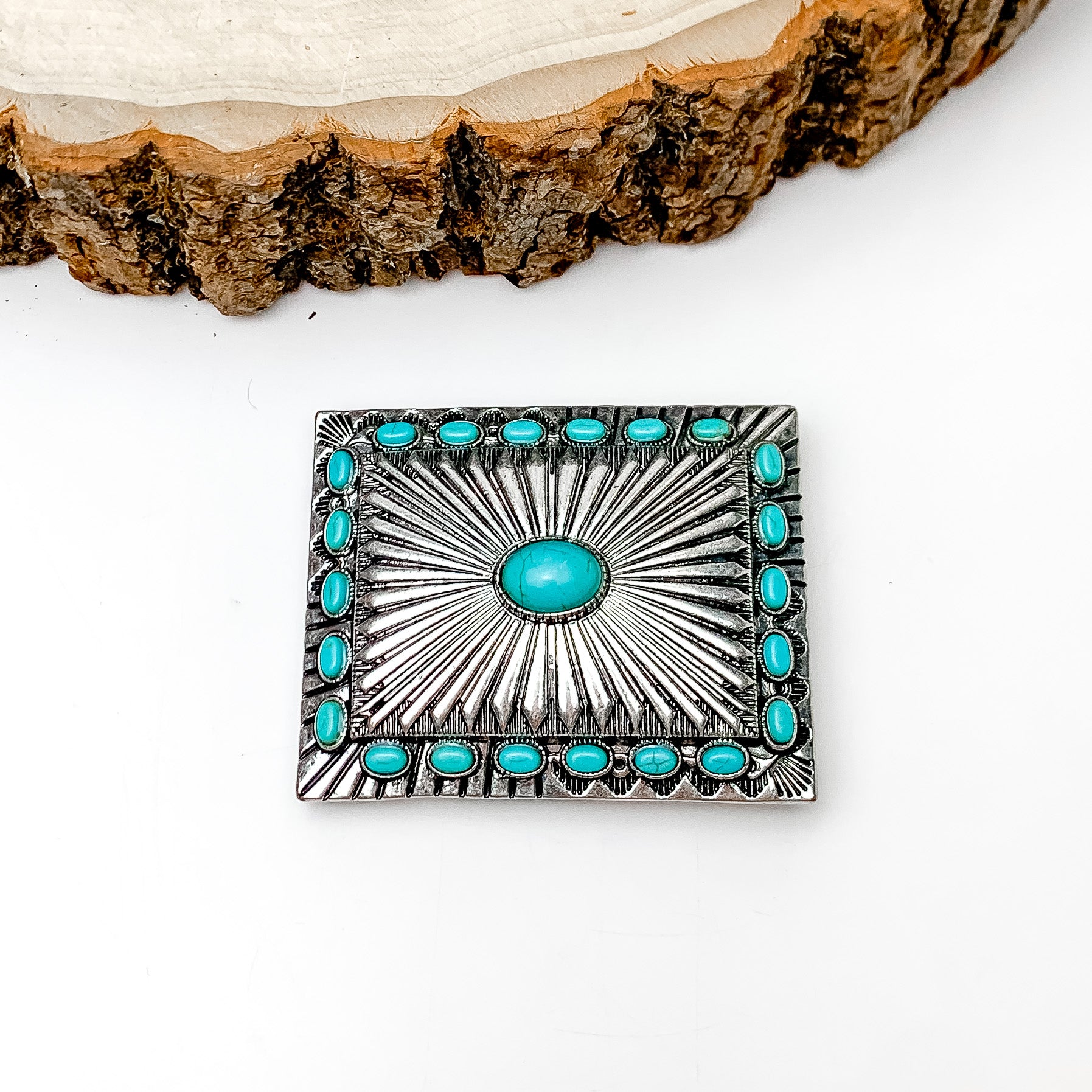 Turquoise Blue Stoned Rectangle Belt Buckle in Silver Tone. Pictured on a white background with a wood piece on the top. 