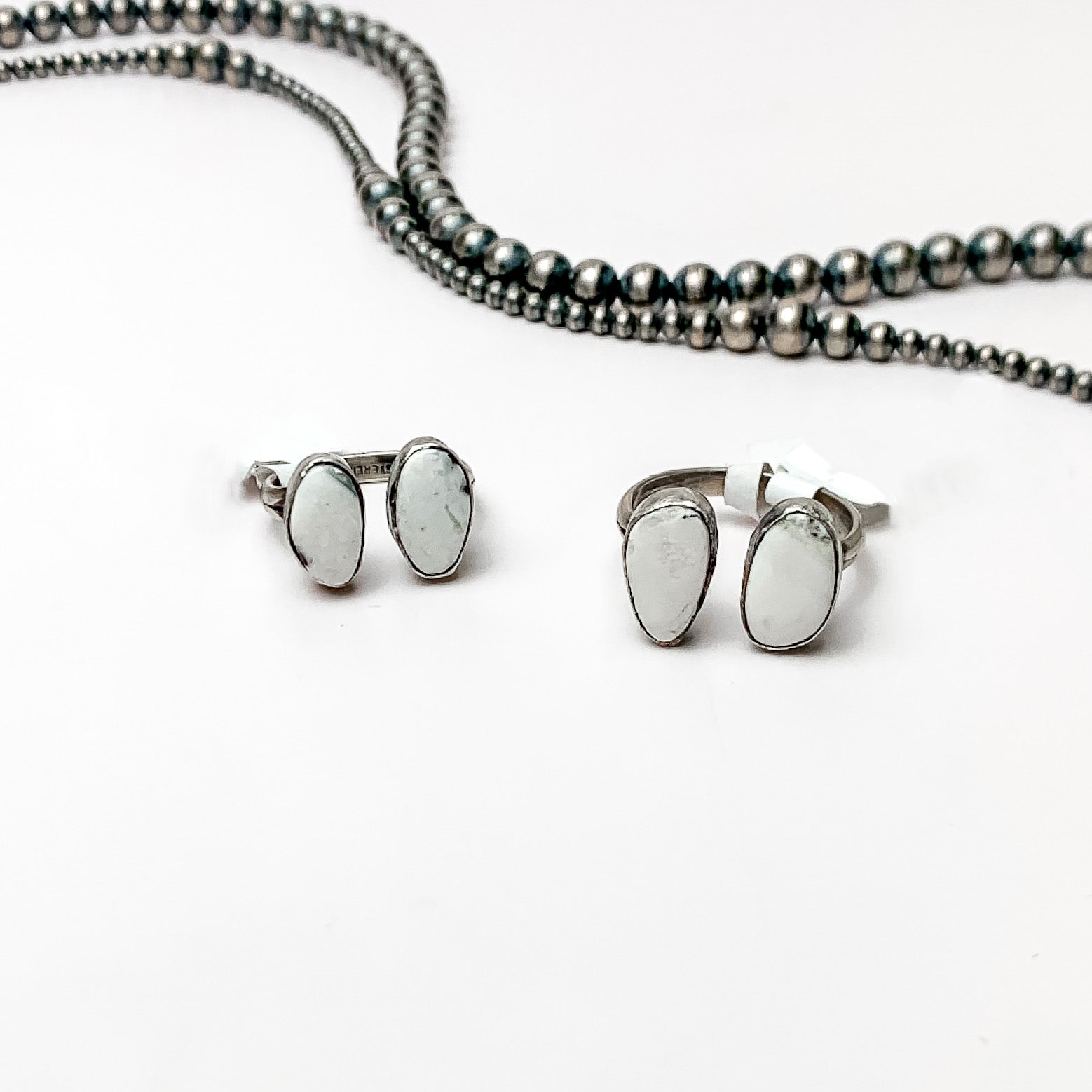 Two silver rings with white buffalo stones pictured on a white background with silver beads. 