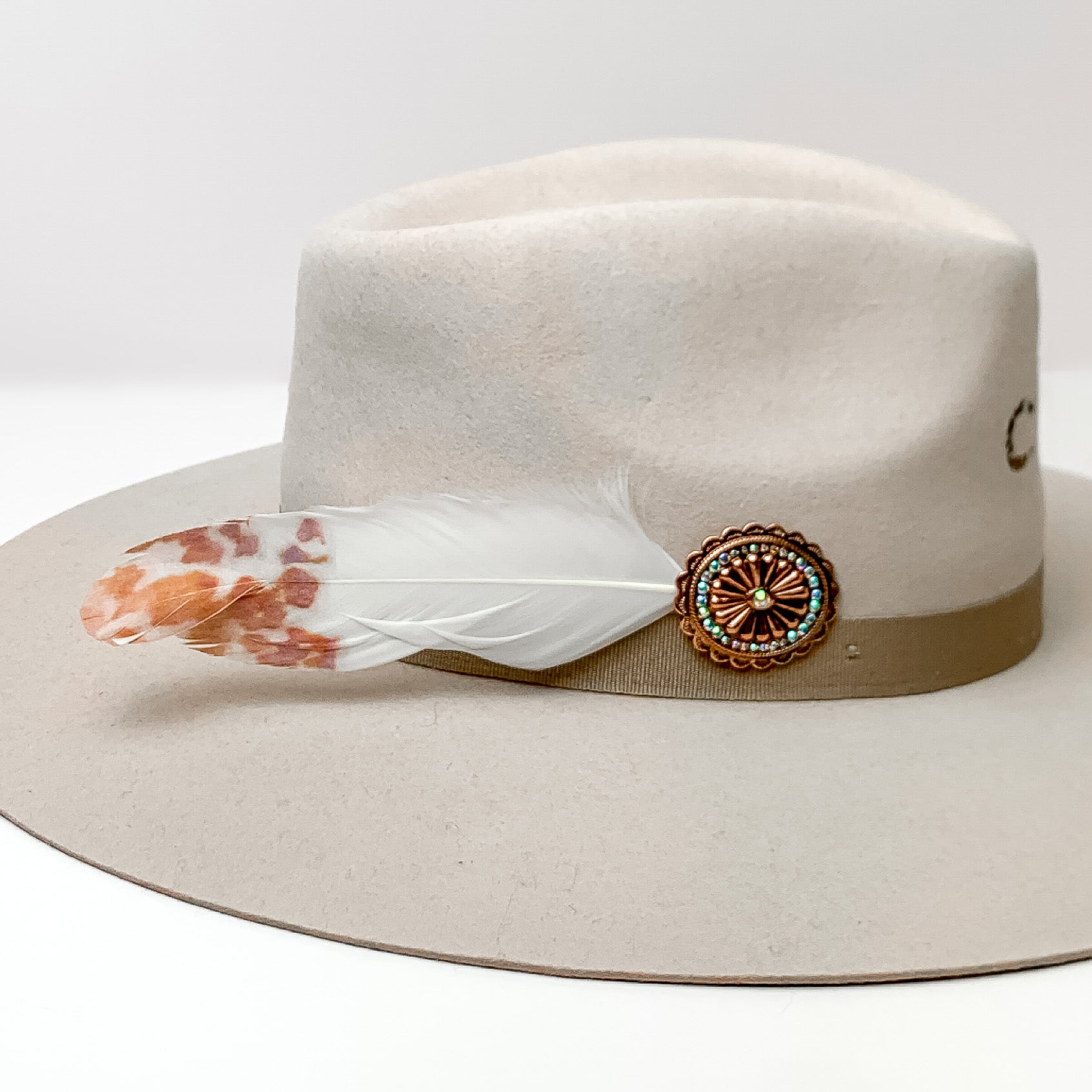 Oval Concho With white and orange Feathers Hat Pin With AB crystals. Pictured on a white background with the pin on the side of a light grey/ brown hat.