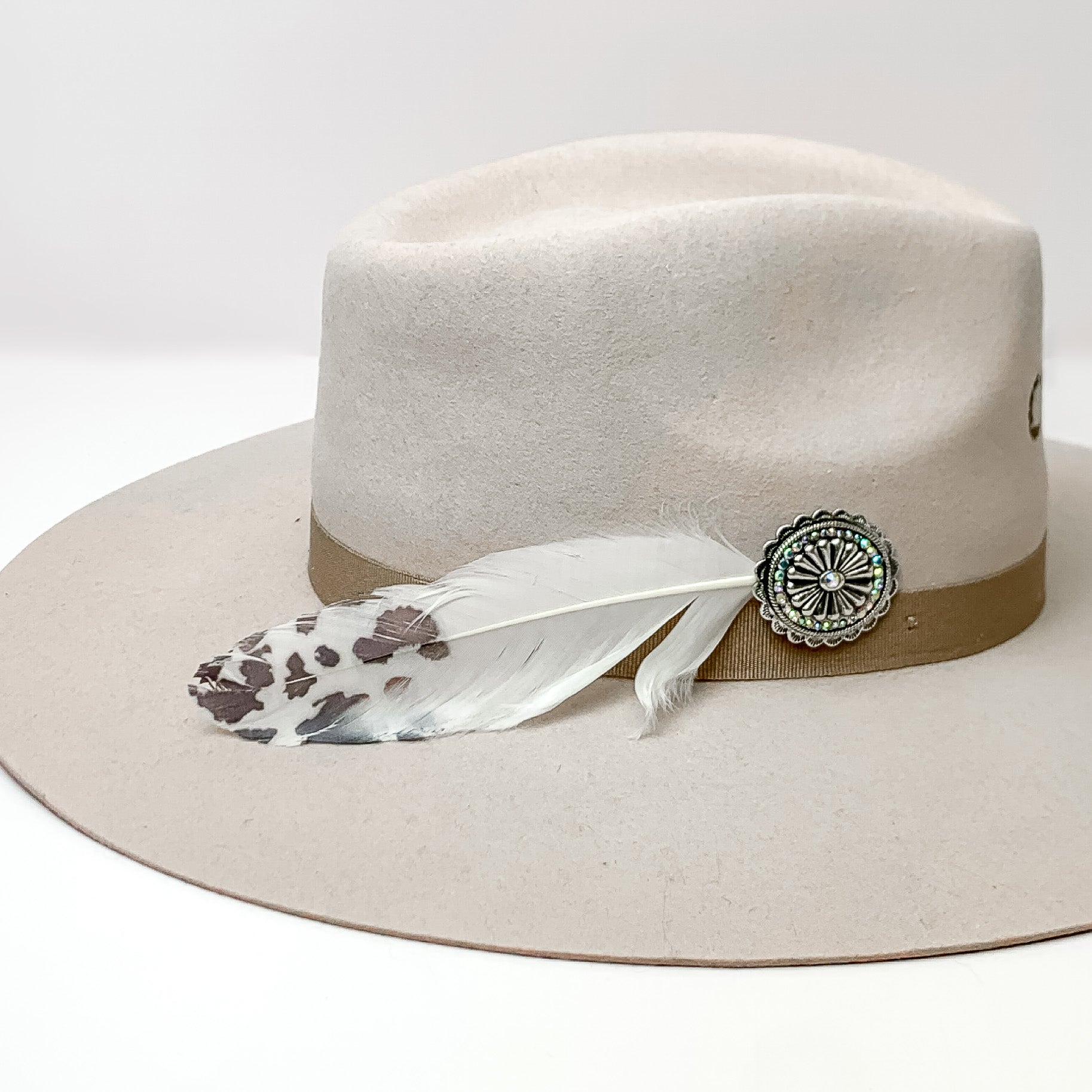 Oval Concho With white and black Feathers Hat Pin With AB crystals. Pictured on a white background with the pin on the side of a light grey/ brown hat.