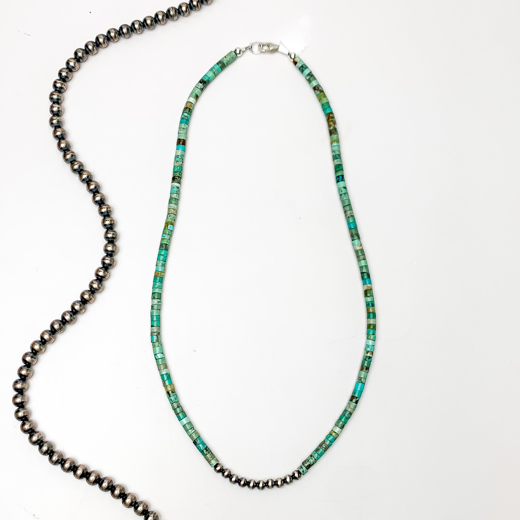 Turquoise chip necklace with silver pearls in the middle of the necklace. This necklace is pictured on a white background with silver beads on the left side. 