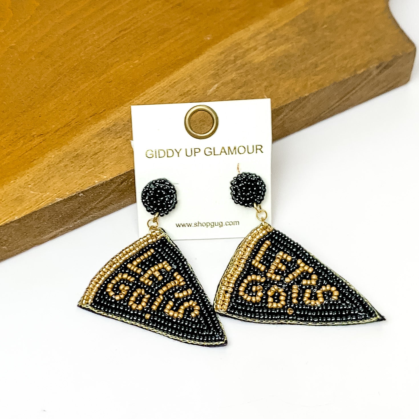 Lets Go Beaded Flag Earrings in black. Pictured on a white background with the earrings laying against a wood piece.