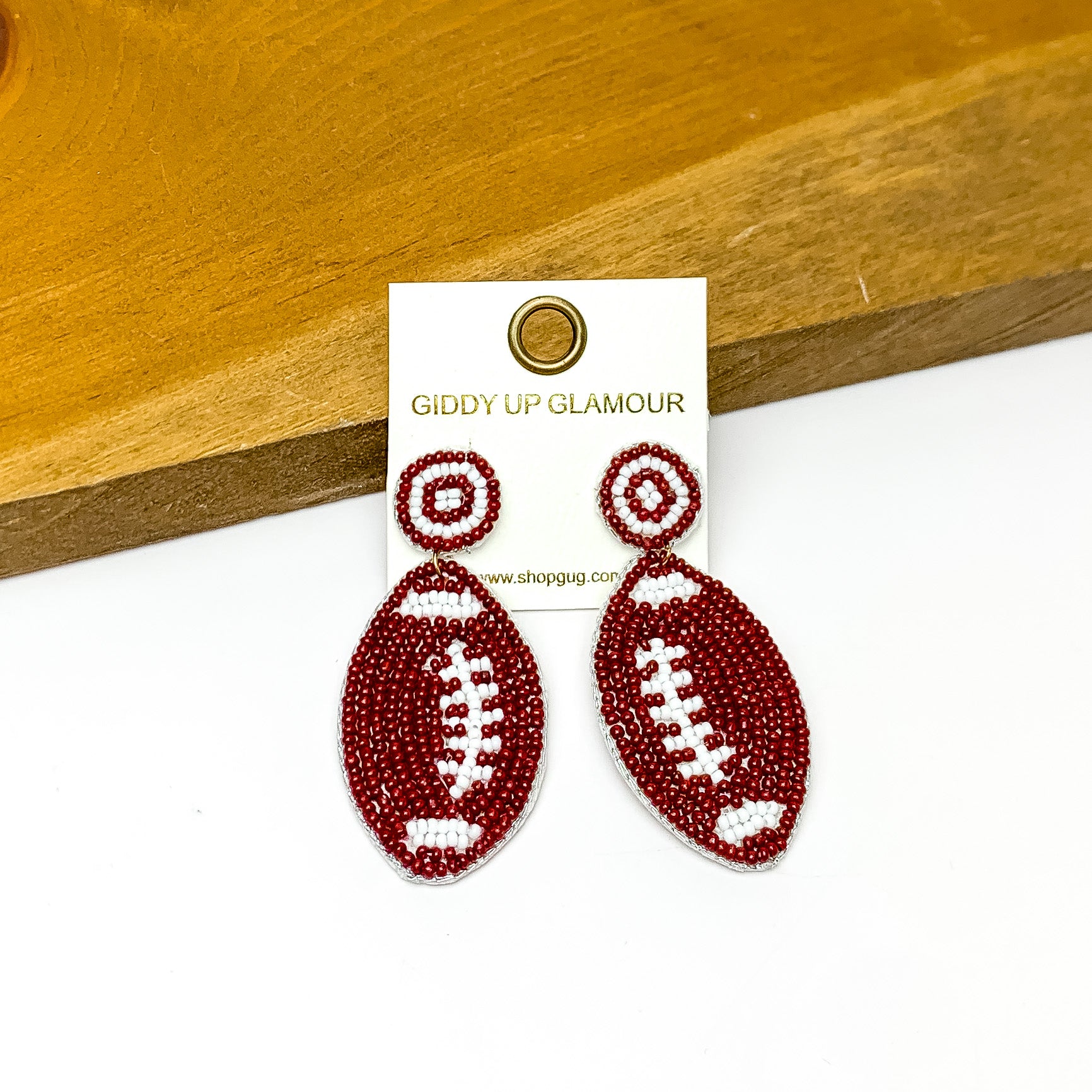 Football Post Beaded Earrings in Brown and White. Pictured on a white background with the earrings against a wood piece.