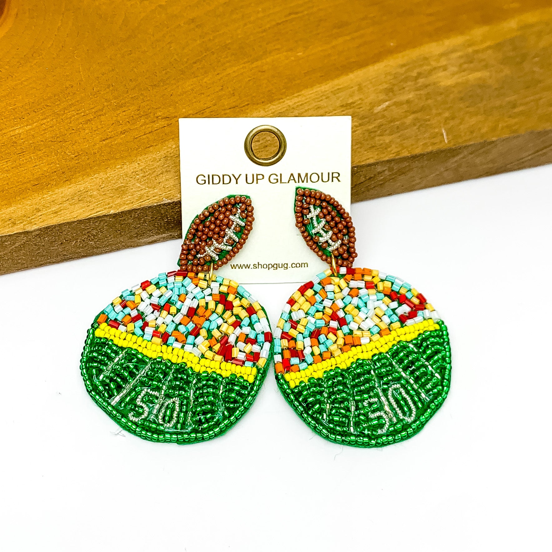 Football Stadium Circular Post Beaded Earrings in Multicolor. Pictured against a wood piece with a white background.