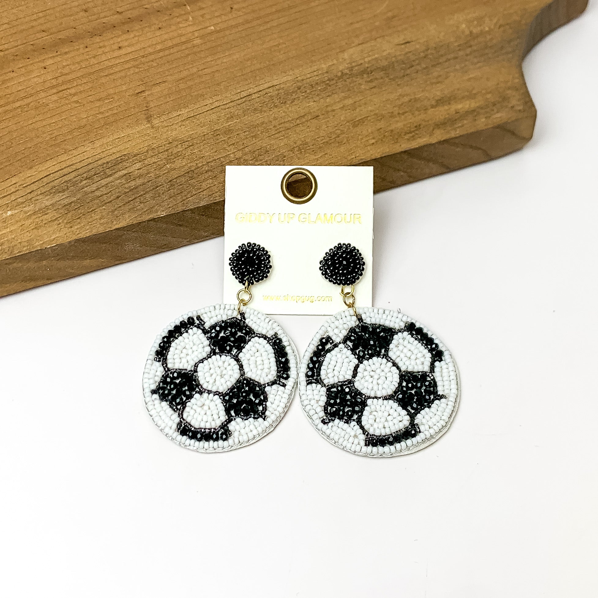 Soccer ball Circular Beaded Earrings in White. Pictured on a white background with the earrings against a wood piece.