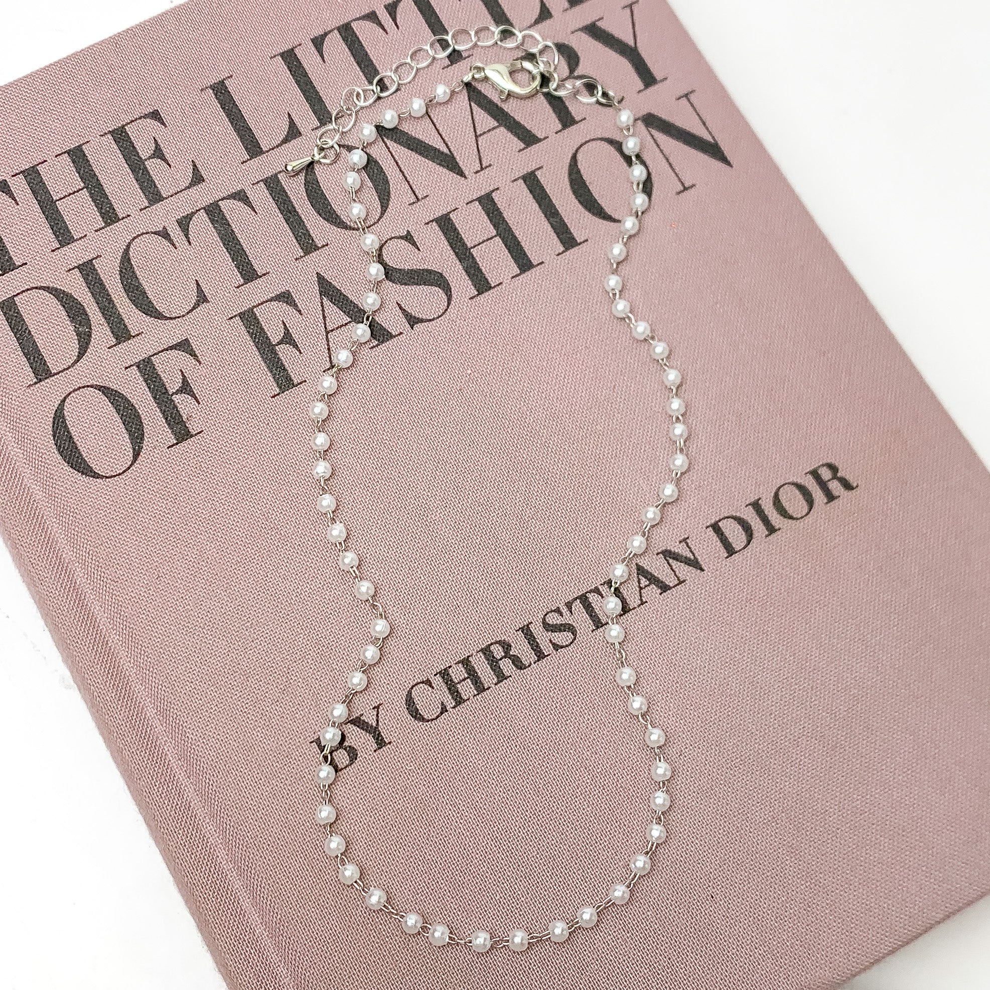 Pearl Linked Necklace in Silver Tone. Pictured on a white background with the necklace laying on a pink book.