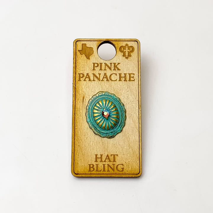 Patina, oval concho hat pin with a center turquoise ab crystal. This hat pin is pictured on a wooden Pink Panache holder on a white background. 