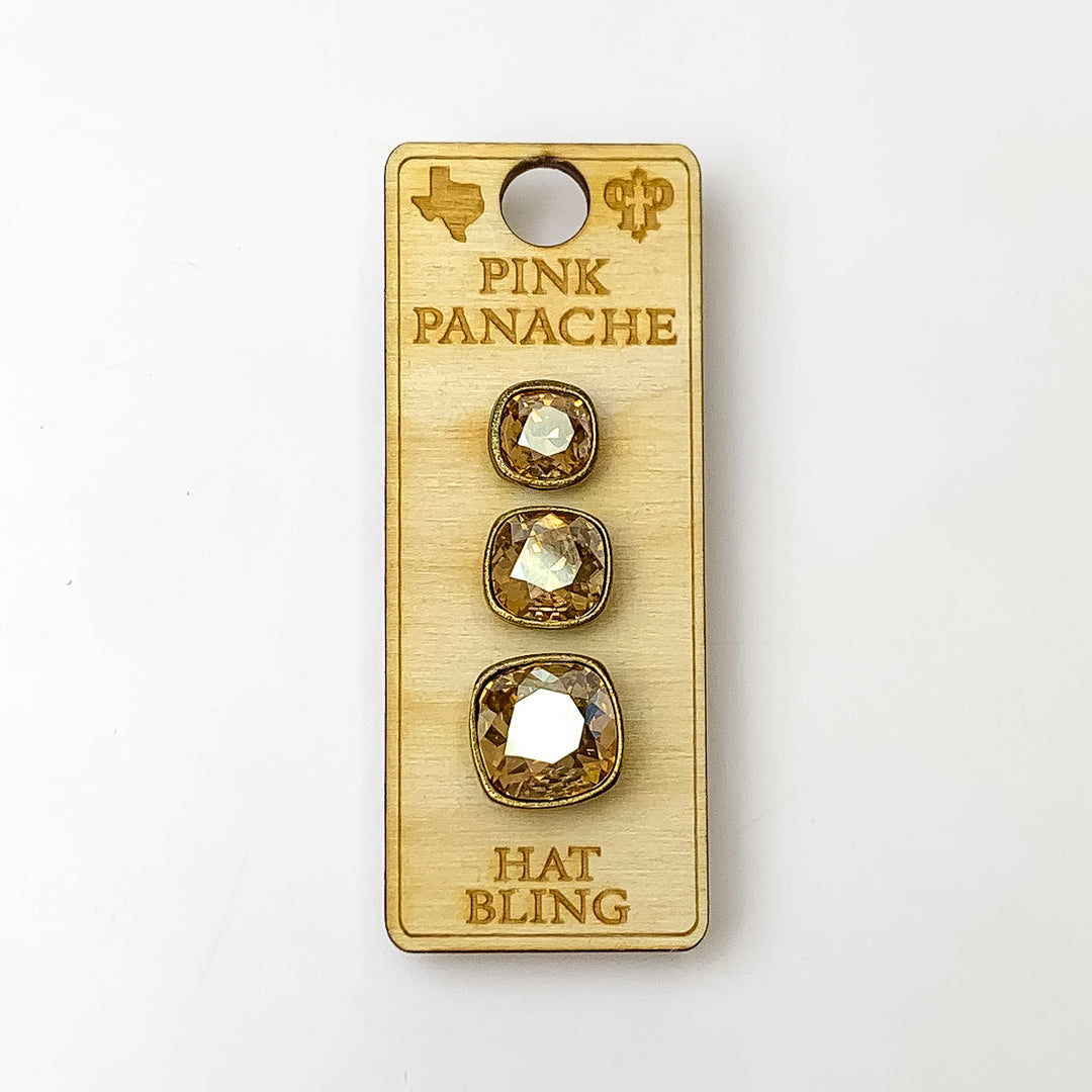 Three bronze, square hat pins going smallest to biggest with golden shadow cushion cut crystal. This hat pin is pictured on a wooden Pink Panache holder on a white background.