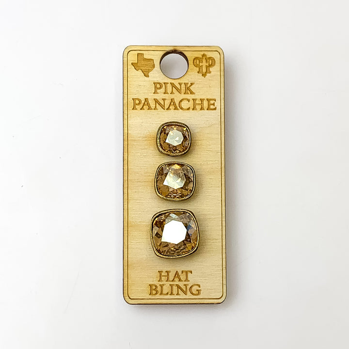 Three bronze, square hat pins going smallest to biggest with golden shadow cushion cut crystal. This hat pin is pictured on a wooden Pink Panache holder on a white background.