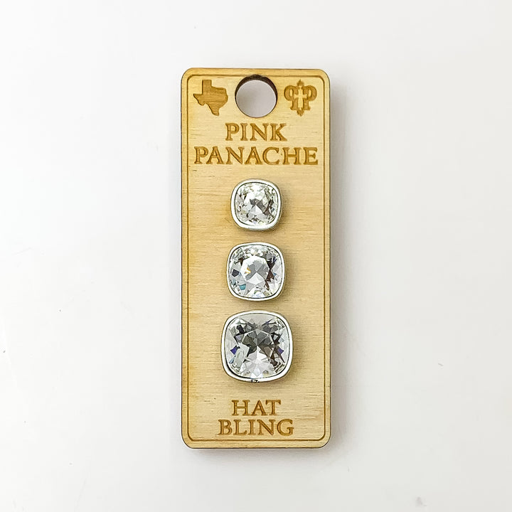 Three silver, square hat pin going smallest to biggest with clear cushion cut crystal. These hat pins is pictured on a wooden Pink Panache holder on a white background.