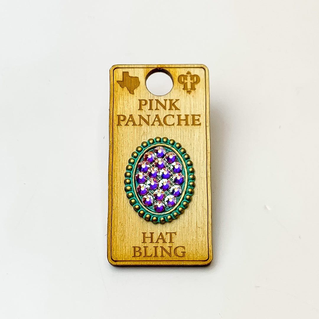 Patina, oval hat pin with a turquoise ab crystal inlay. This hat pin is pictured on a wooden Pink Panache holder on a white background.