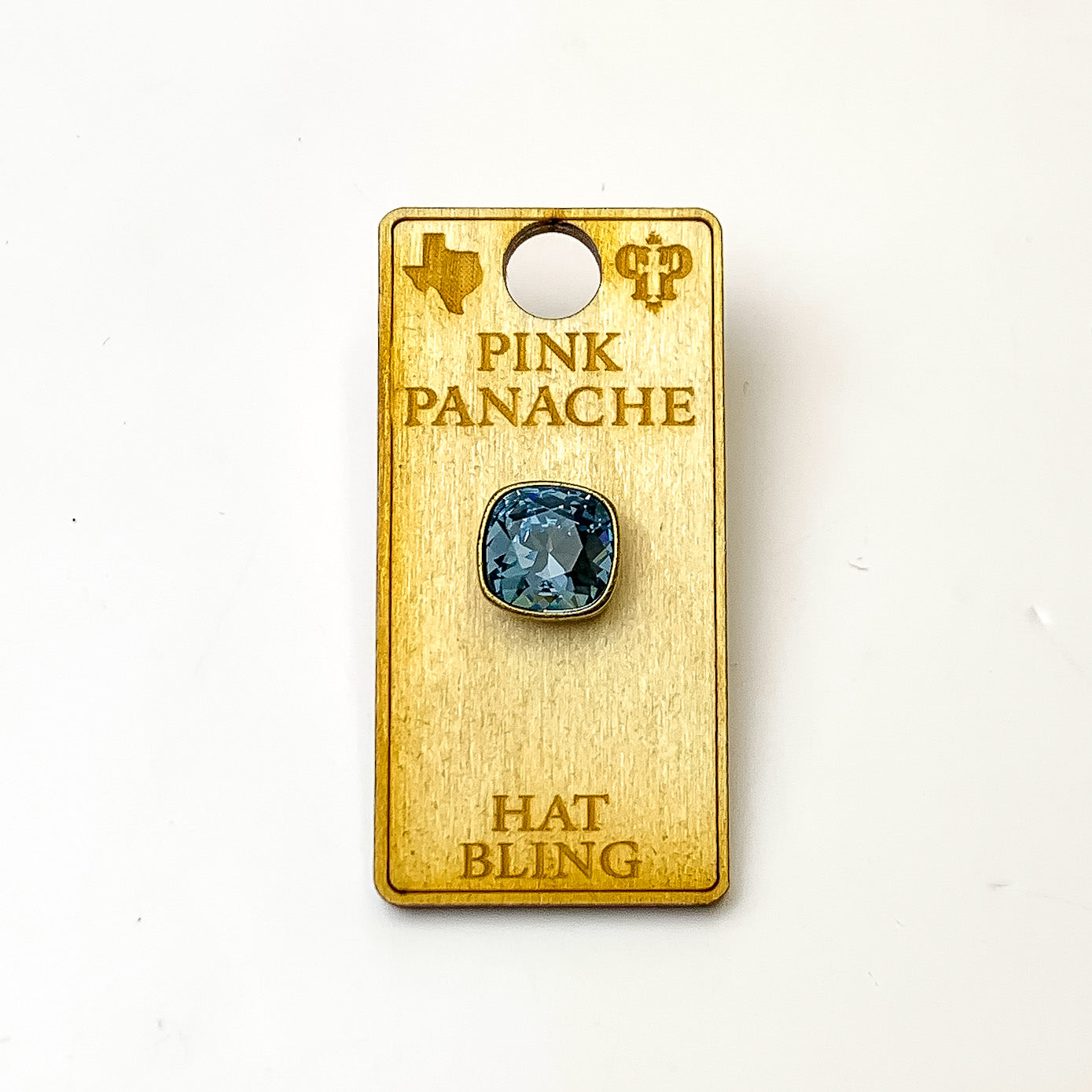Bronze, square hat pin with a denim blue cushion cut crystal. This hat pin is pictured on a wooden Pink Panache holder on a white background.