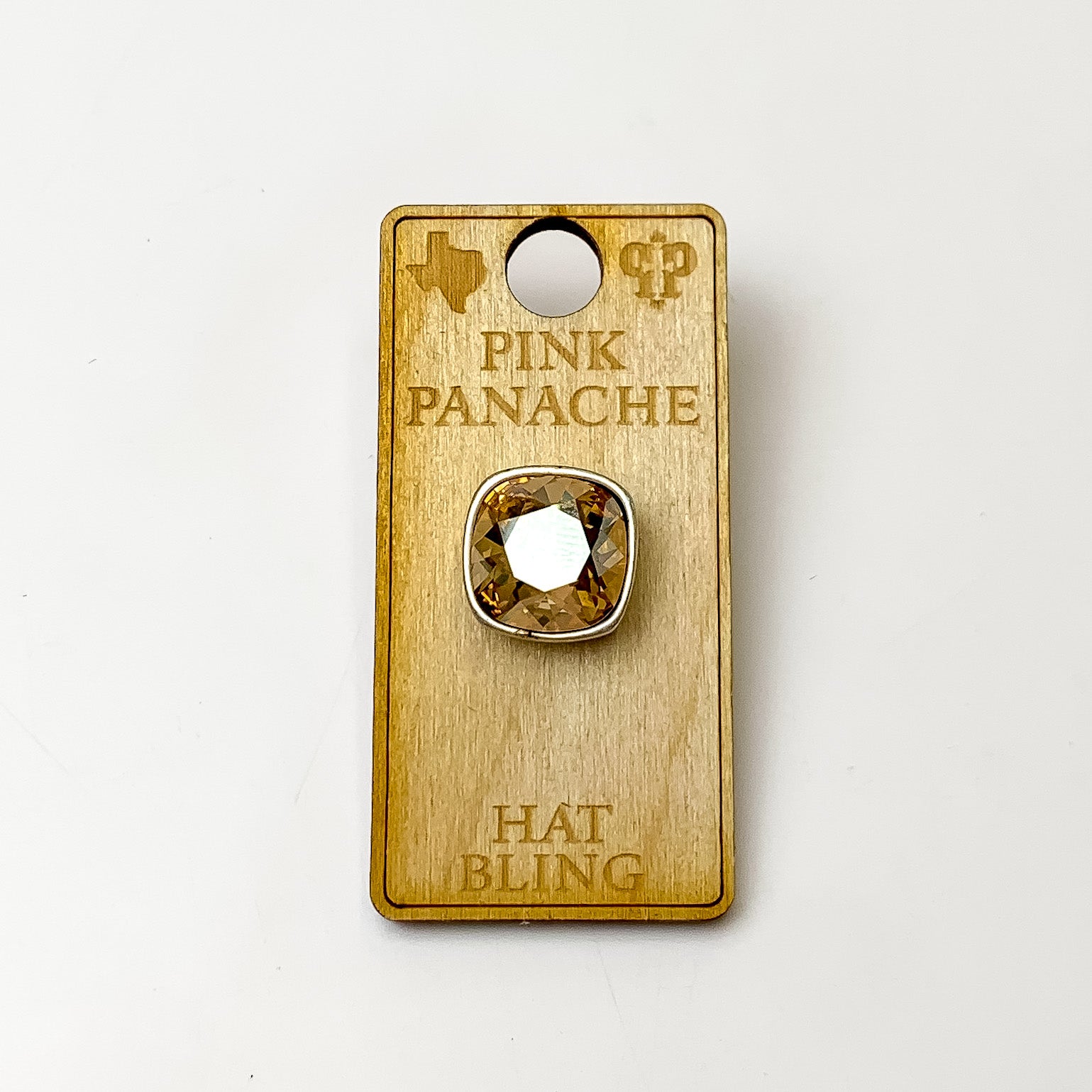 Silver, square hat pin with a golden shadow cushion cut crystal. This hat pin is pictured on a wooden Pink Panache holder on a white background.